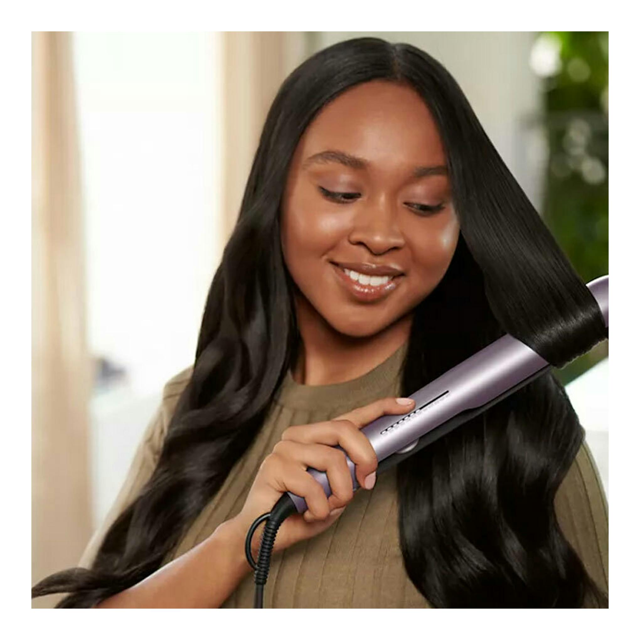Plancha de pelo Philips BHS530/00 lila en uso, alisando el cabello negro de una mujer.