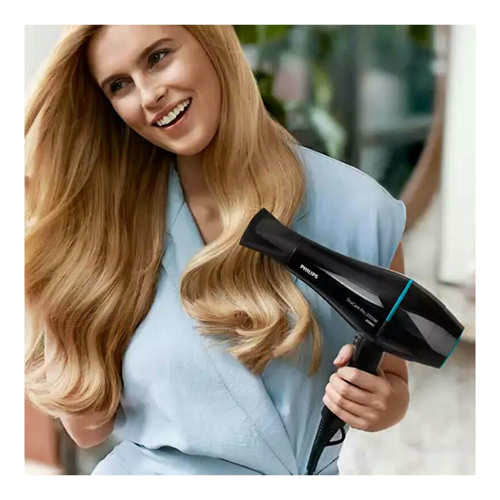 Secador Philips BHD272/00 negro con detalles azules, sostenido por una mujer mientras seca su cabello.
