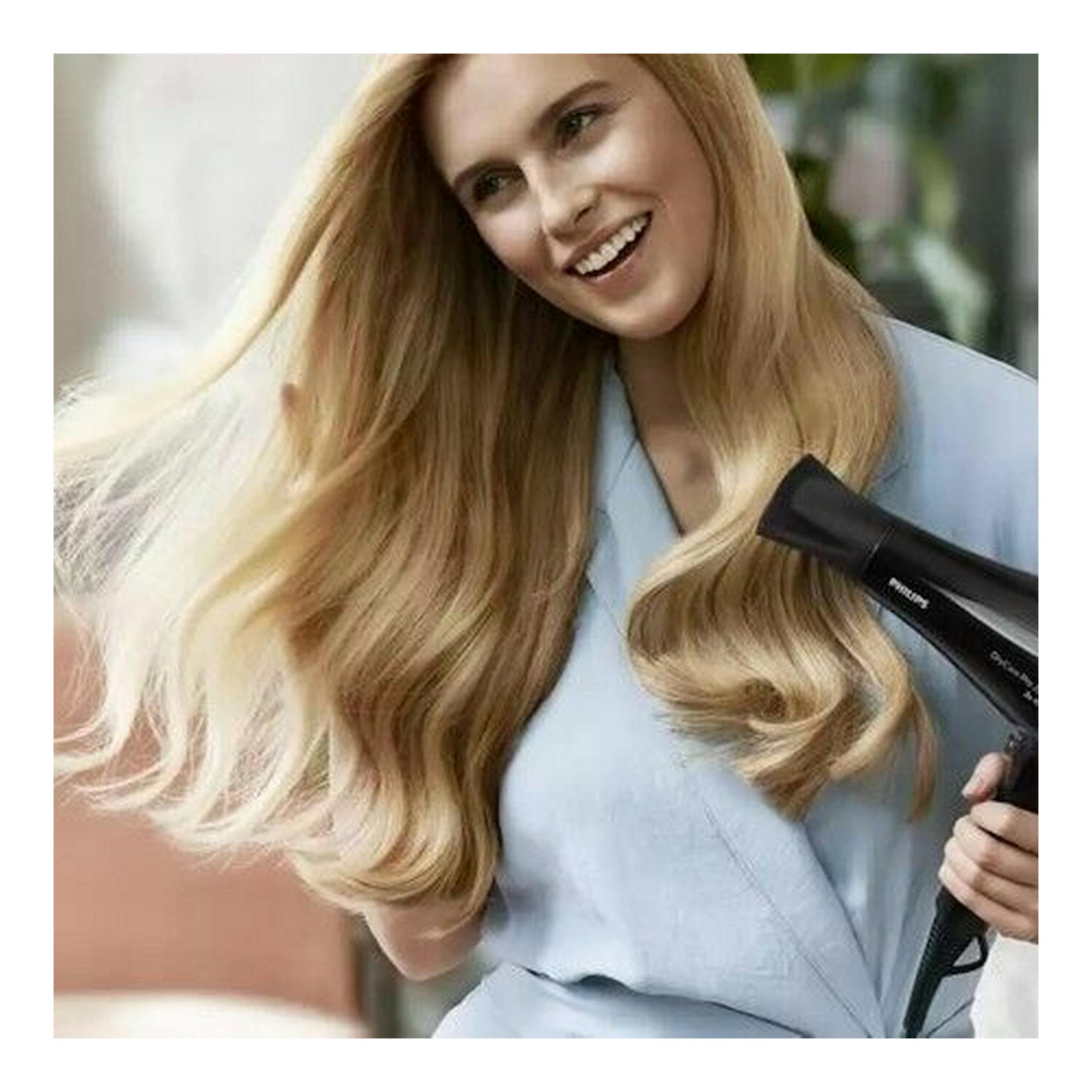 Secador Philips BHD274/00 negro, en vista lateral, apuntando al cabello rubio de una mujer.
