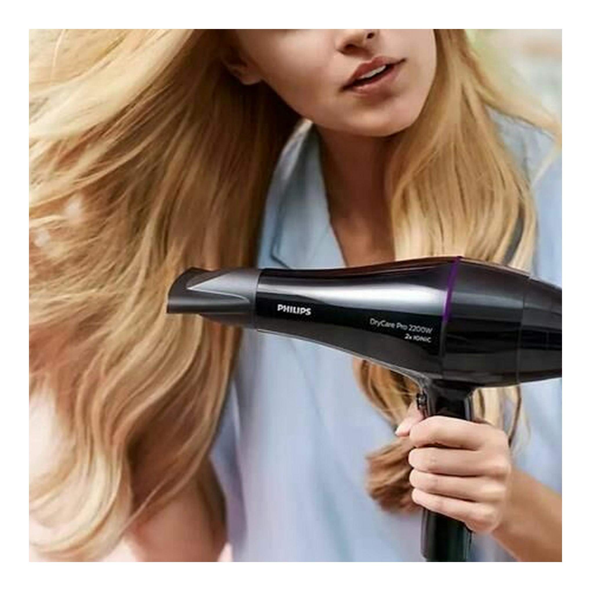 Secador Philips BHD274/00 negro, de perfil, en uso por una mujer rubia.