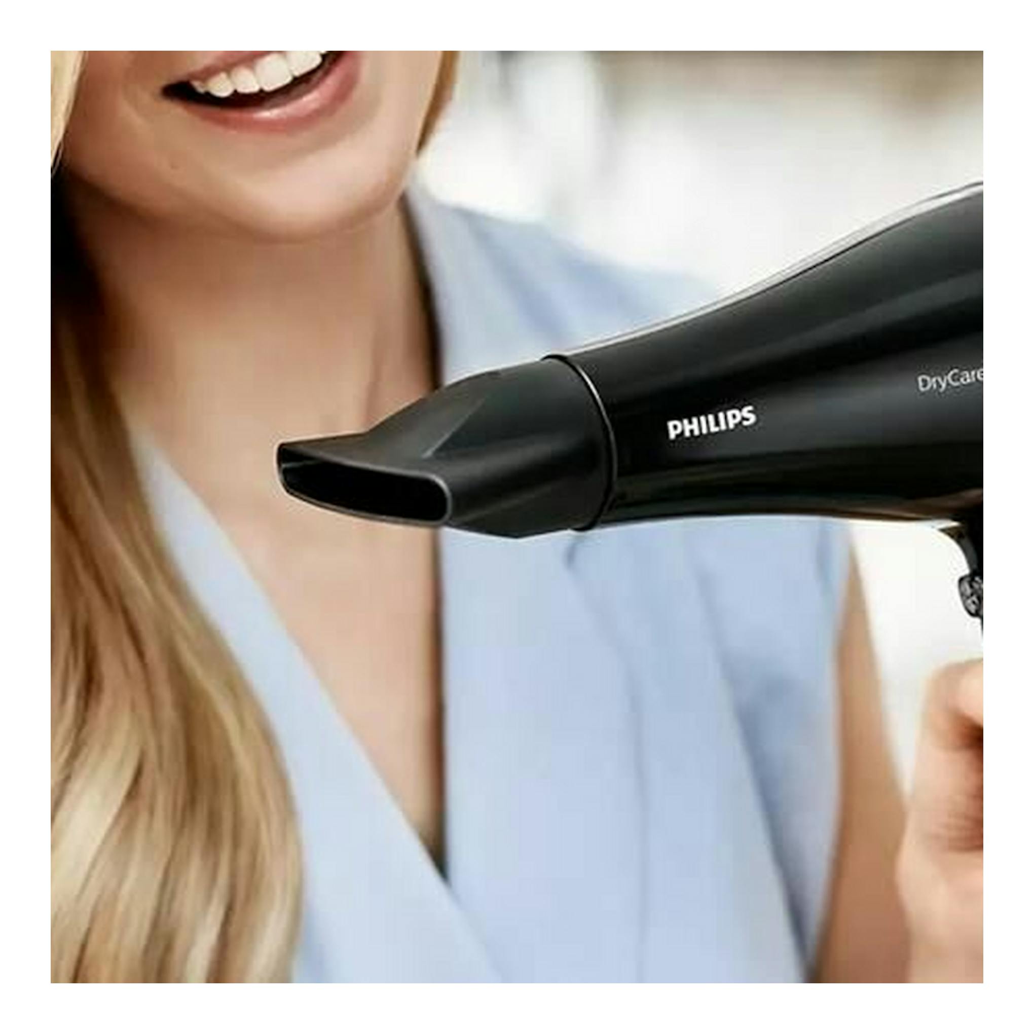 Secador Philips BHD274/00 negro en primer plano, visto de perfil, junto al rostro de una mujer.