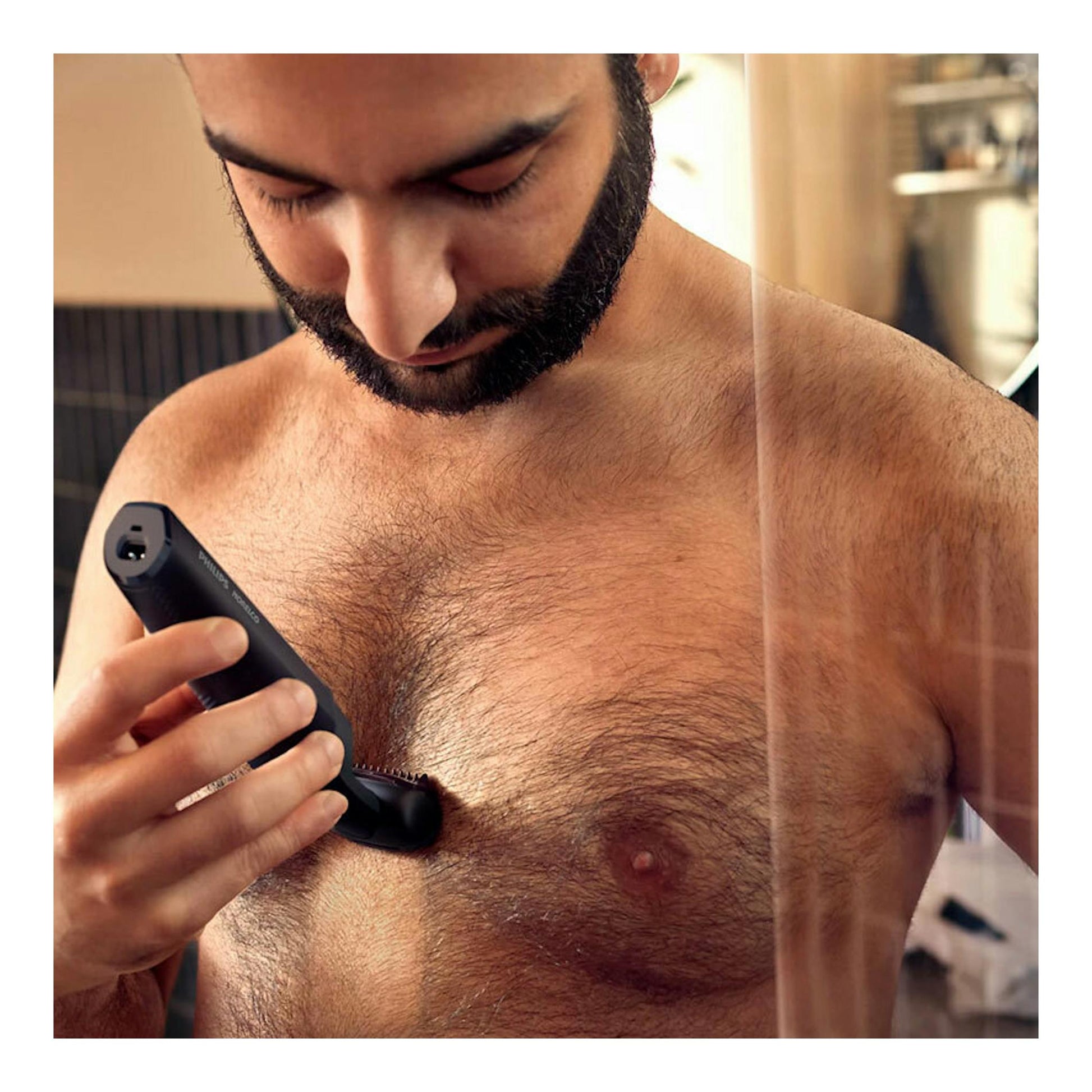 Hombre recortándose el vello del pecho con una afeitadora Philips BG3017/01 negra, vista frontal.