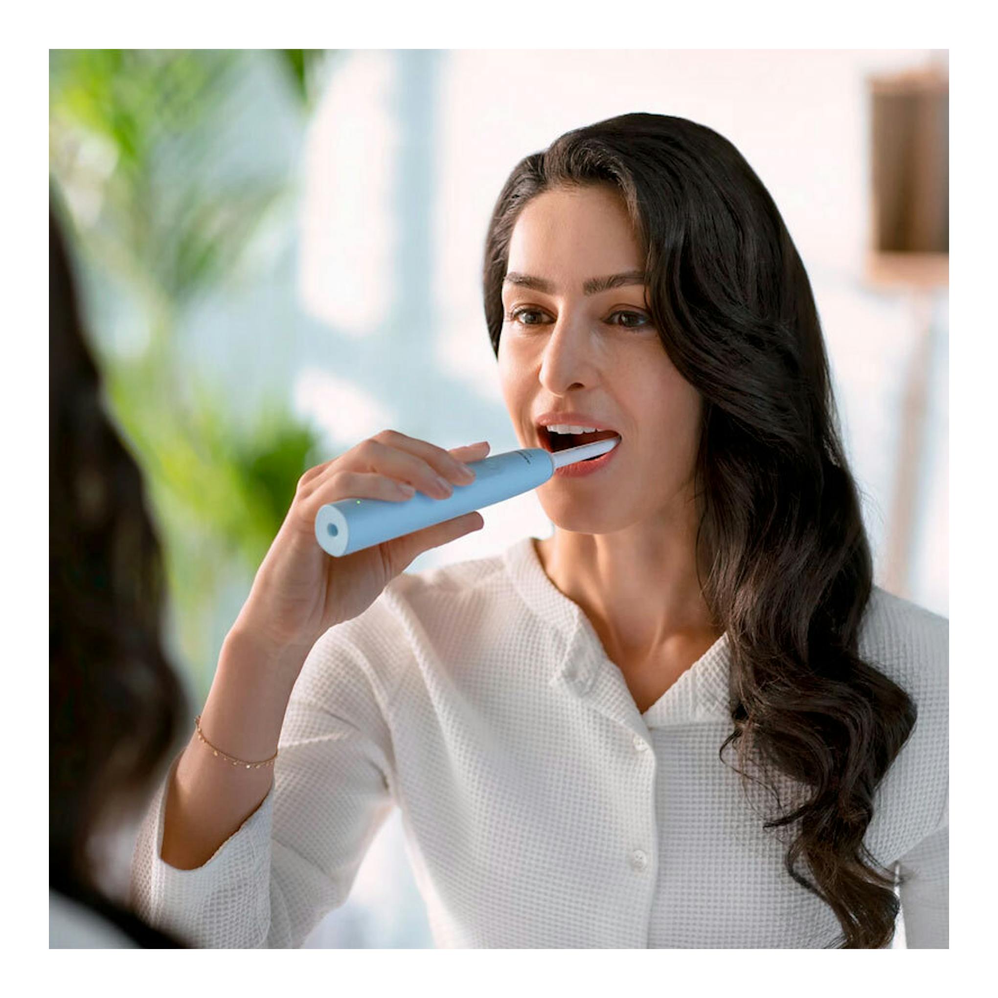 Mujer usando cepillo dental eléctrico Philips HX3651/12 azul claro, vista frontal.