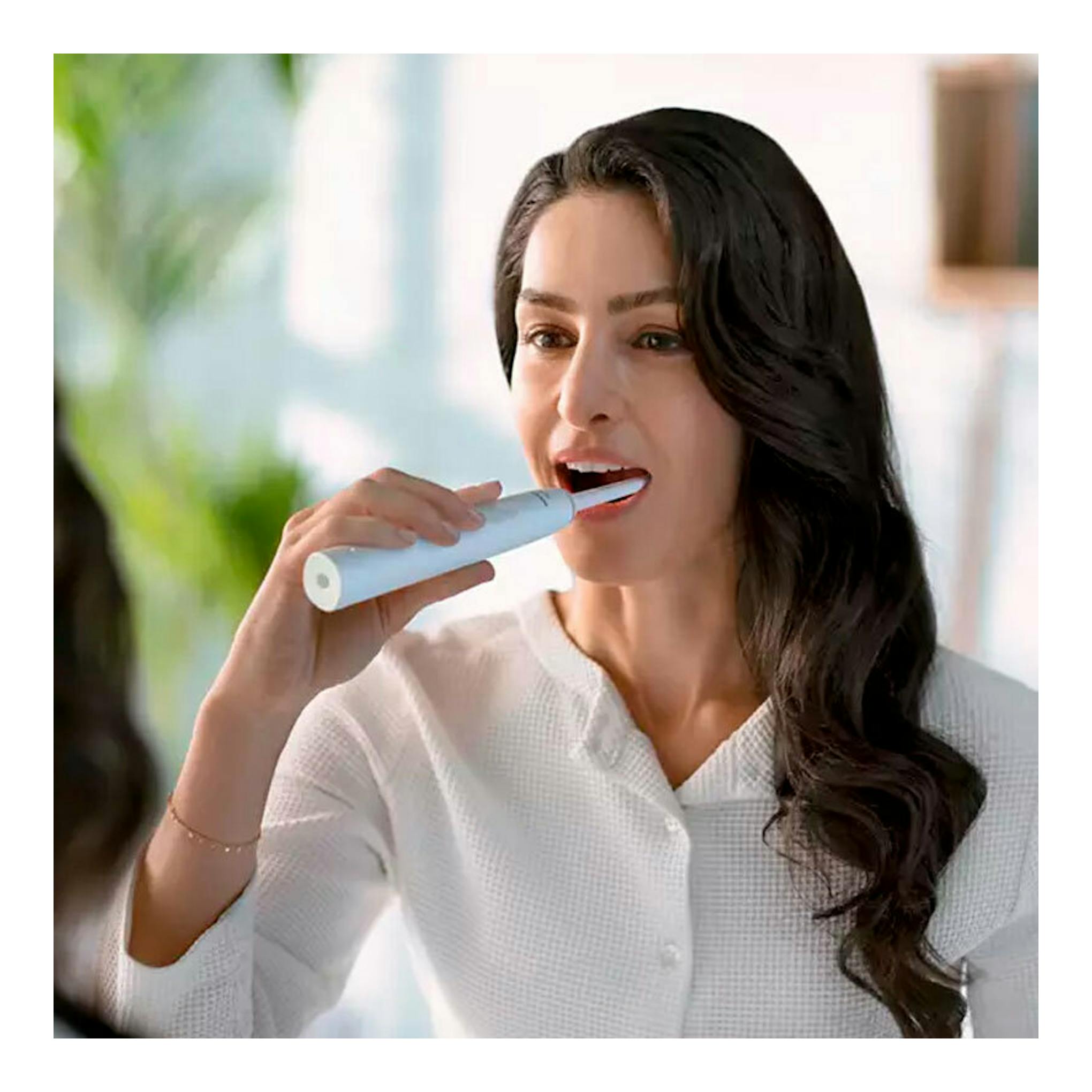 Mujer cepillándose con cepillo dental eléctrico Philips HX3651/13 blanco, vista frontal.
