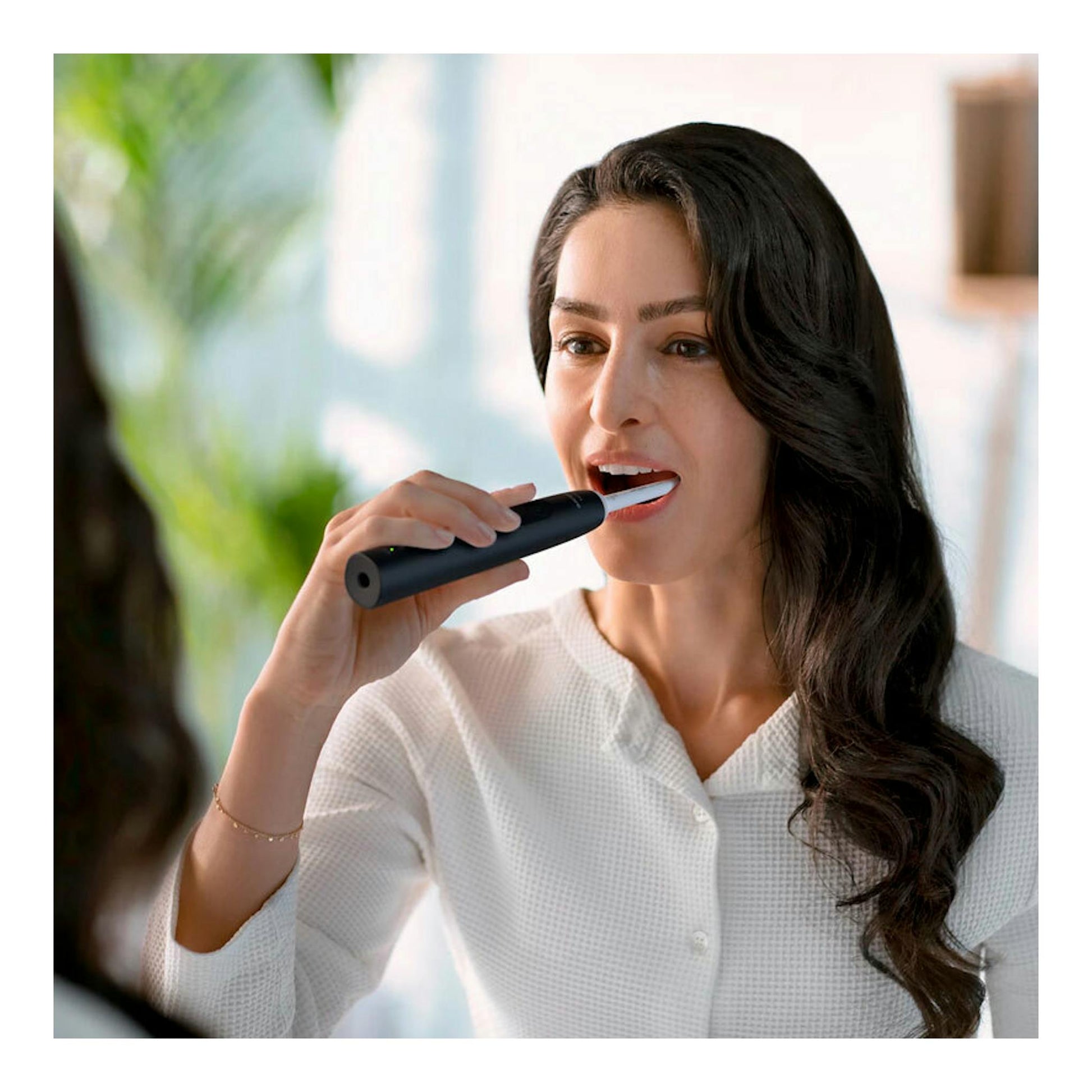 Mujer cepillándose los dientes con un cepillo dental eléctrico Philips HX3671/14 negro, vista frontal.