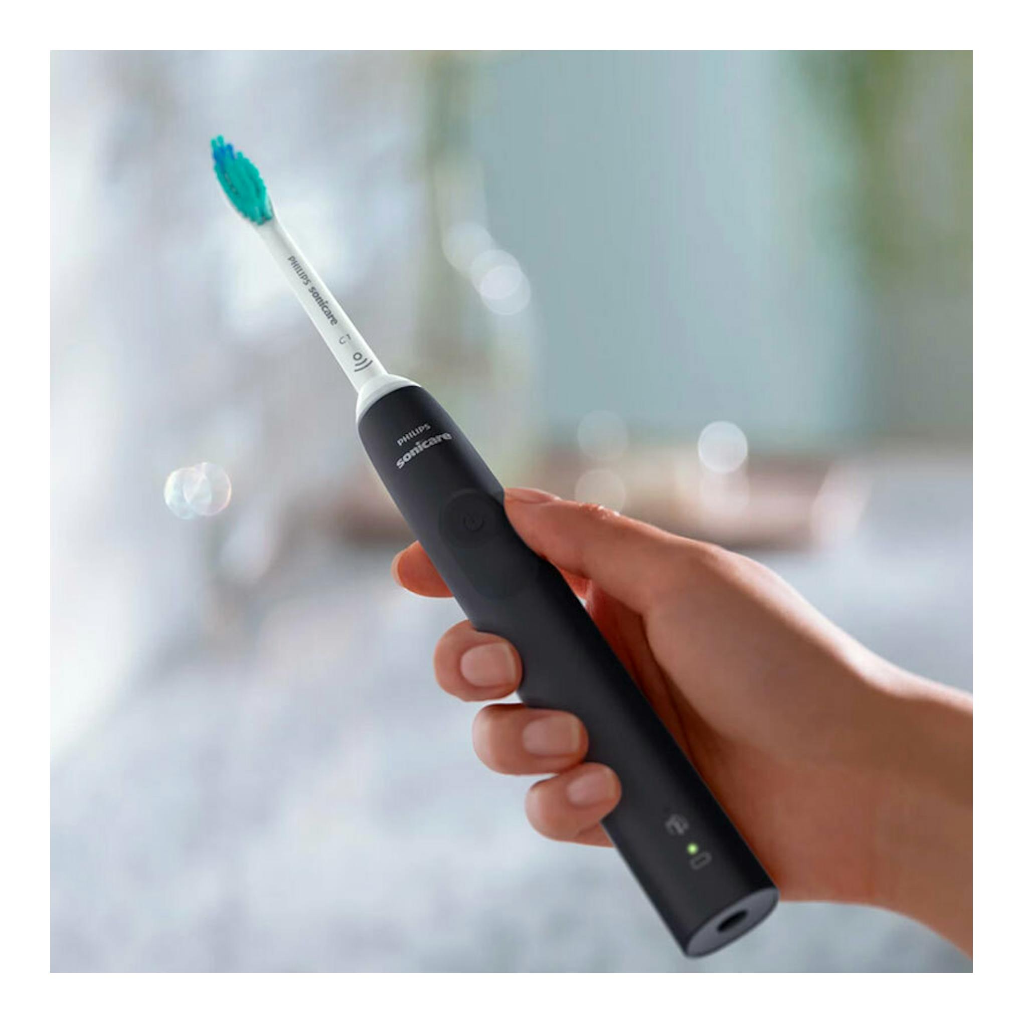 Cepillo dental eléctrico Philips Sonicare HX3671/14 negro, sostenido en la mano, con cabezal blanco y cerdas azules.