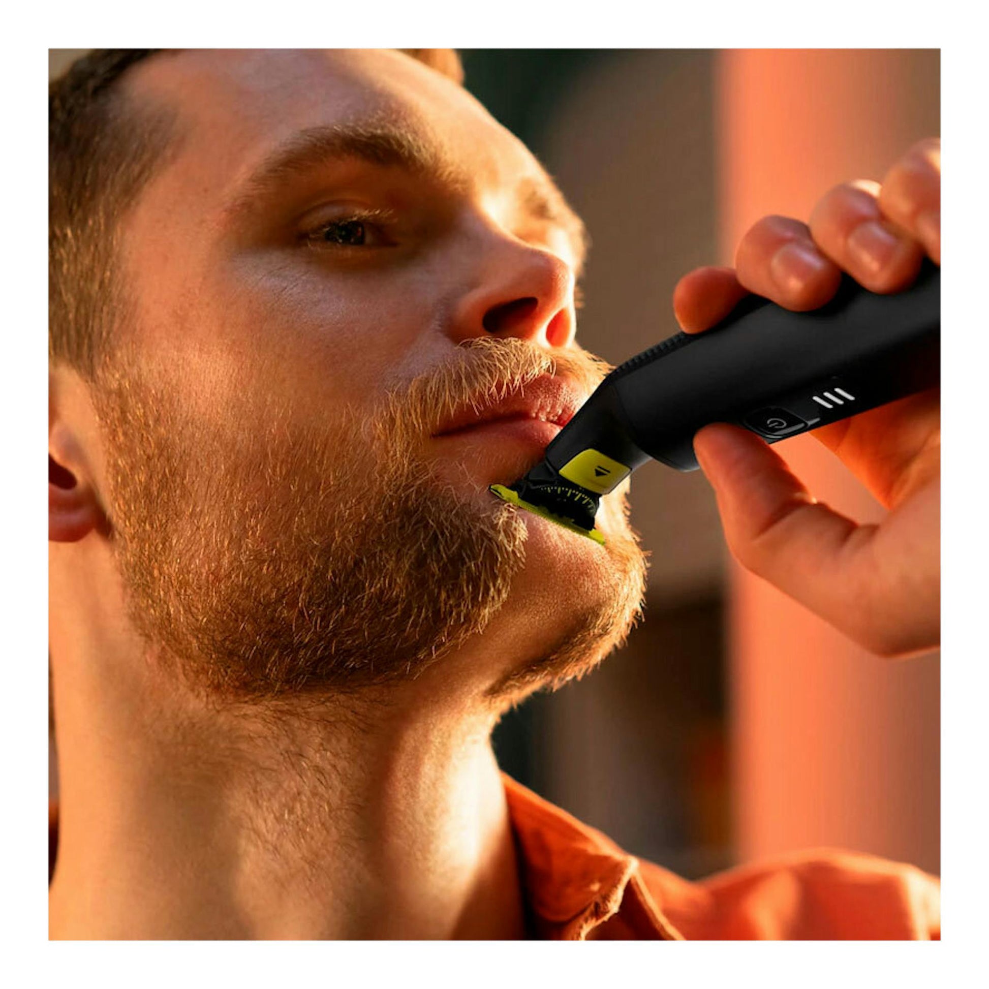 Primer plano de un hombre recortándose la barba con una afeitadora Philips OneBlade QP6542/15 negra y amarilla.
