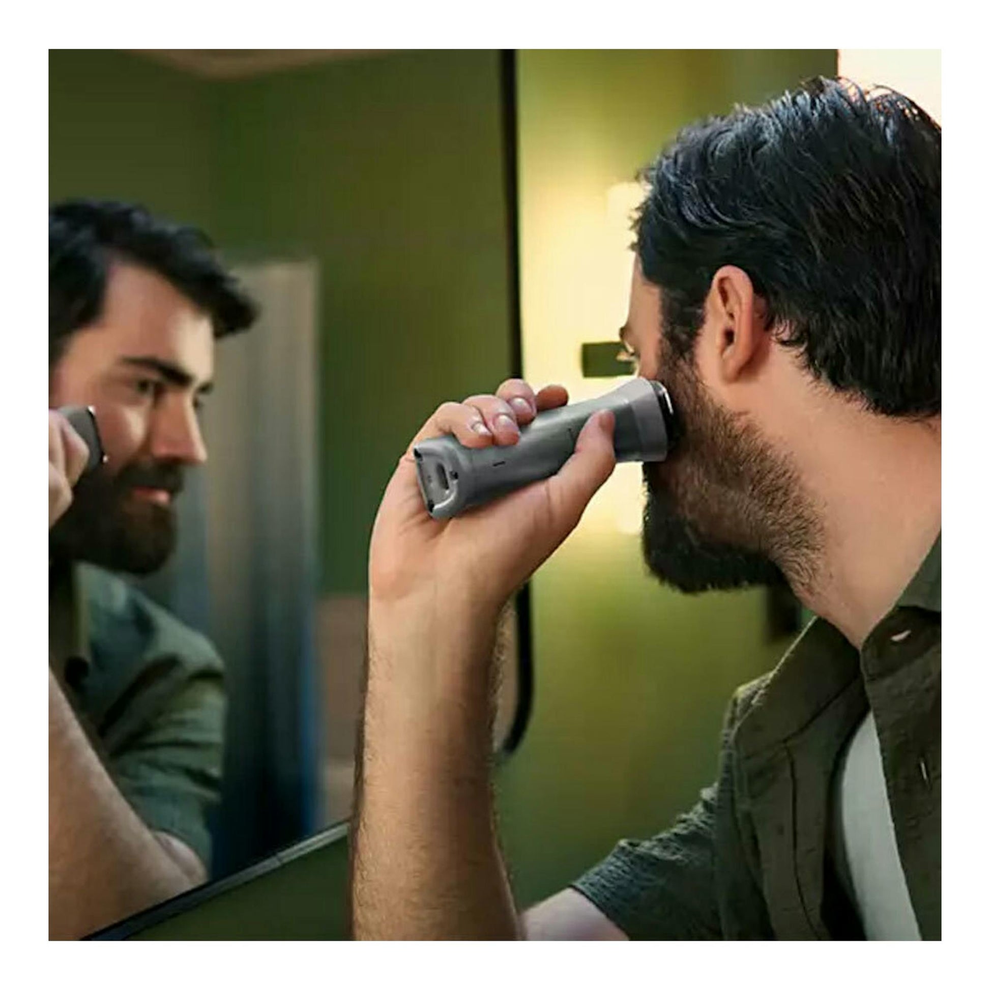 Philips MG5940/15: hombre recortándose la barba con cortapelo gris frente al espejo.