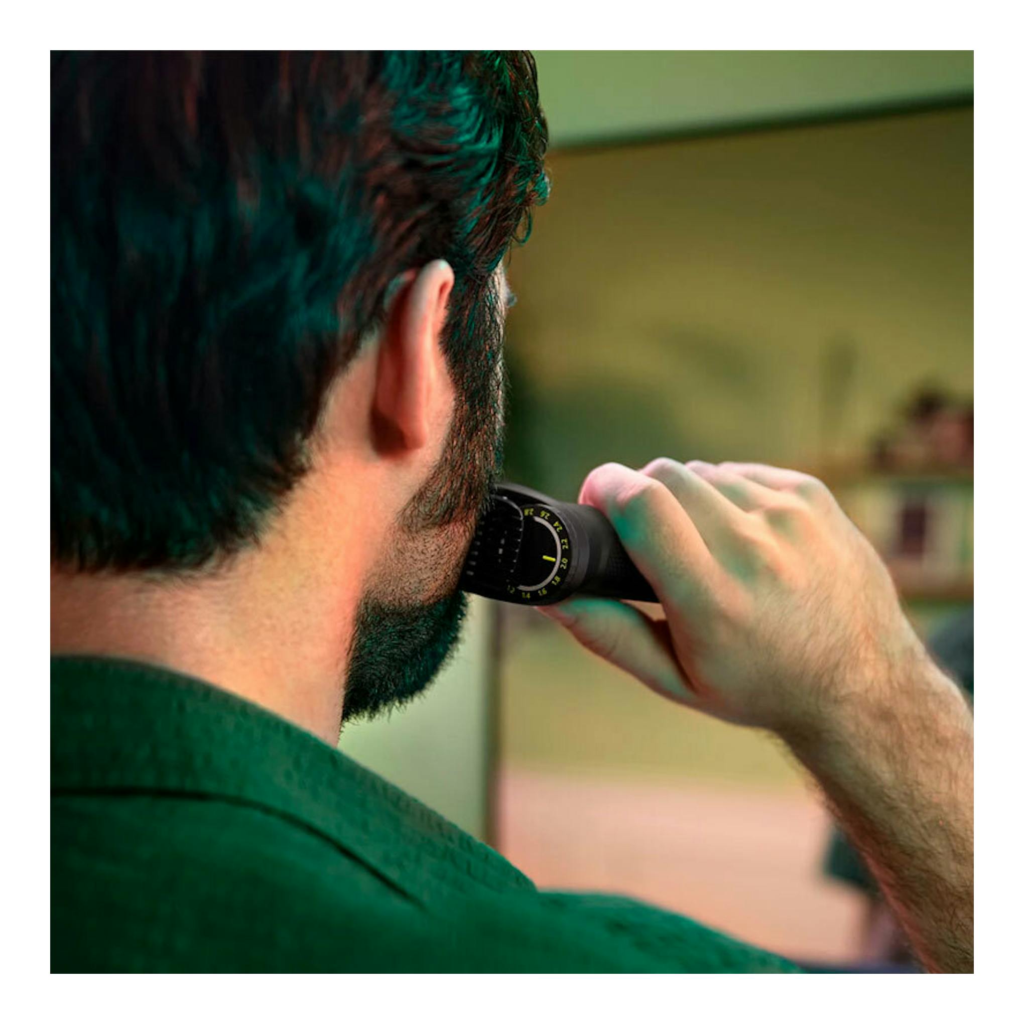Vista trasera de un hombre usando el cortapelos Philips MG7940/15 en la barba, con cuerpo negro.