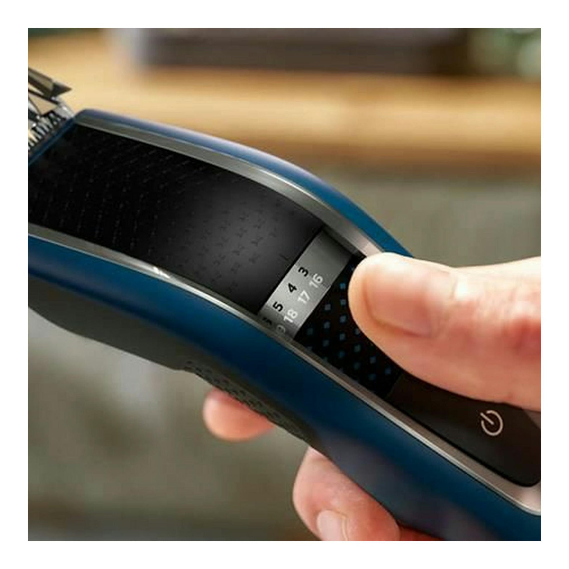 Cortapelo Philips HC5612/15 azul y negro, vista en primer plano con la mano ajustando el selector de longitud.