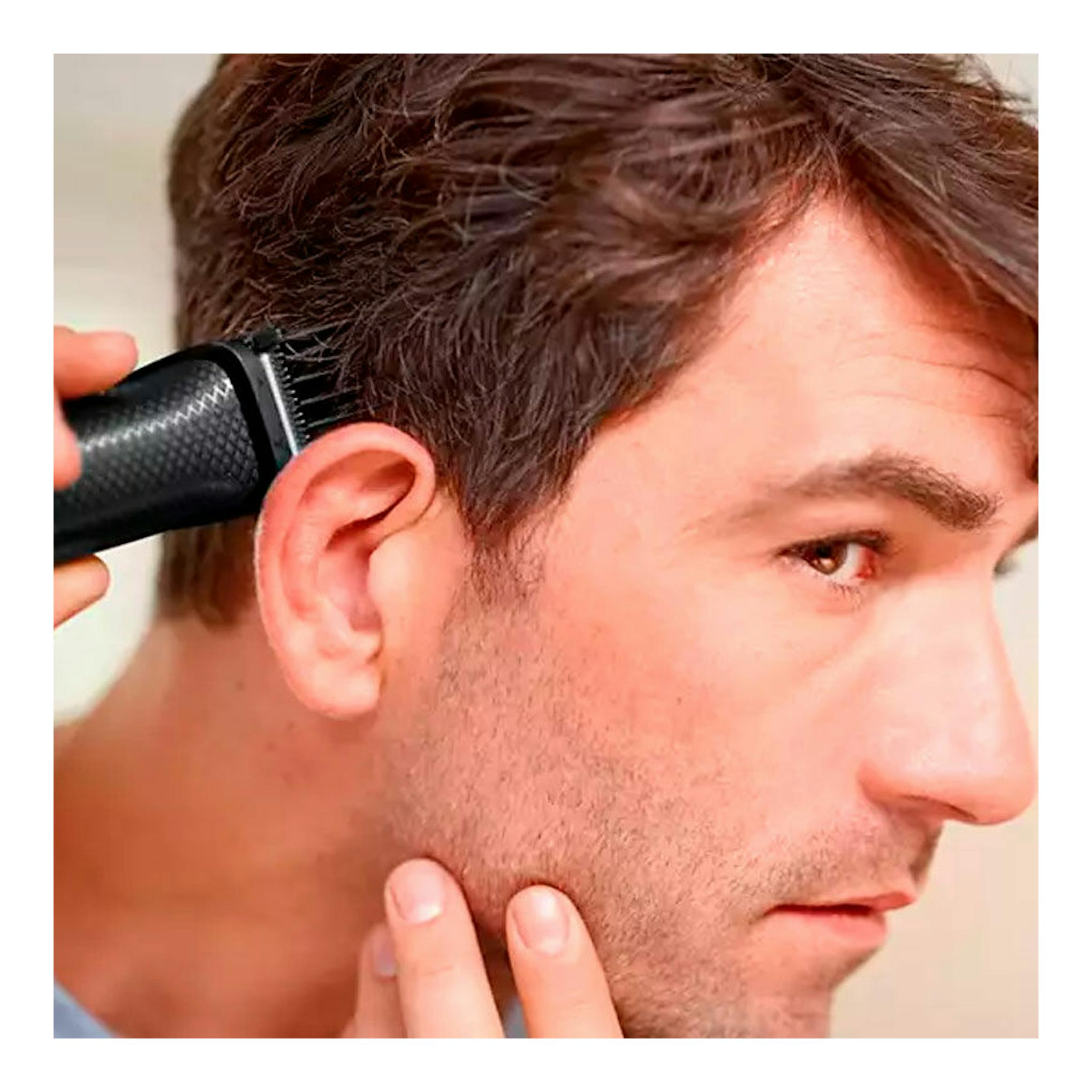 Afeitadora/cortapelos Philips MG3730/15 negra recortando el pelo junto a la oreja de un hombre, vista lateral.