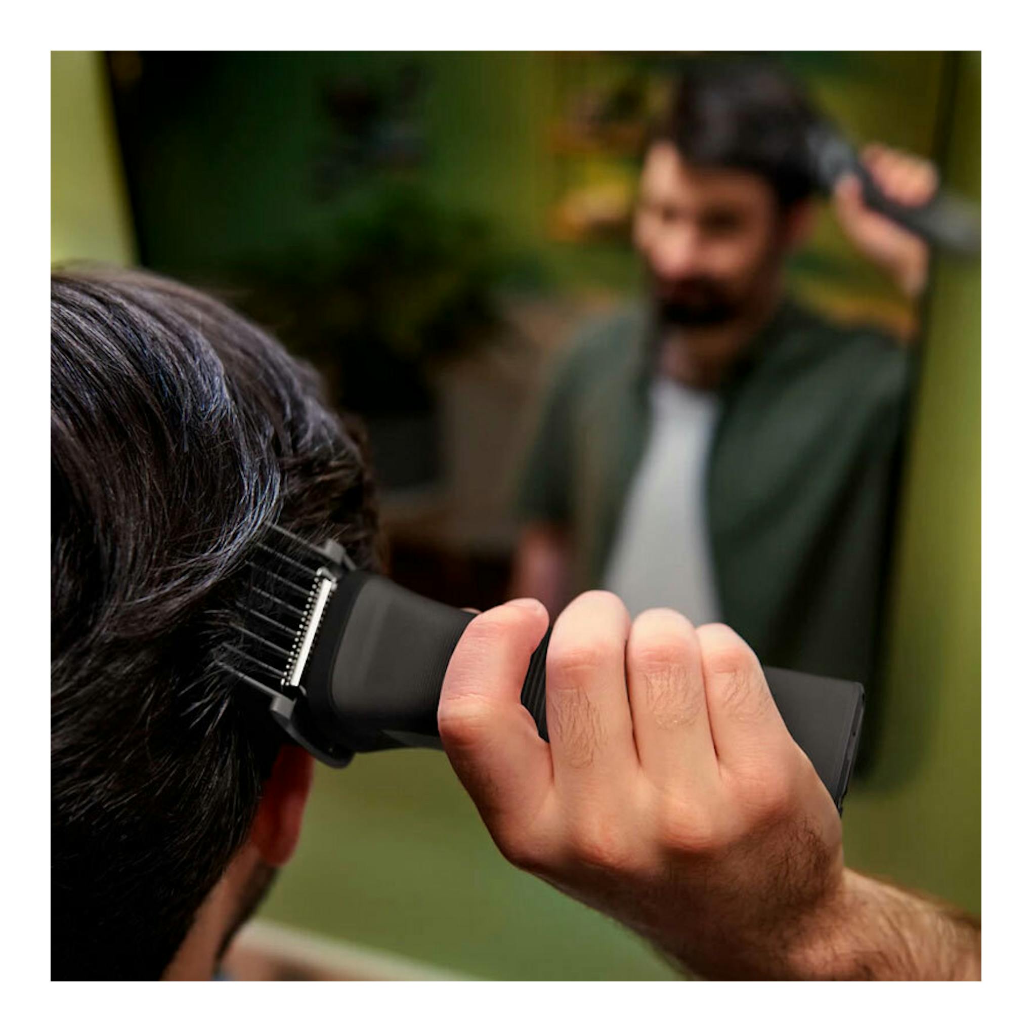 Cortapelos Philips MG7940/15 en uso, vista lateral, recortando el cabello frente a un espejo.