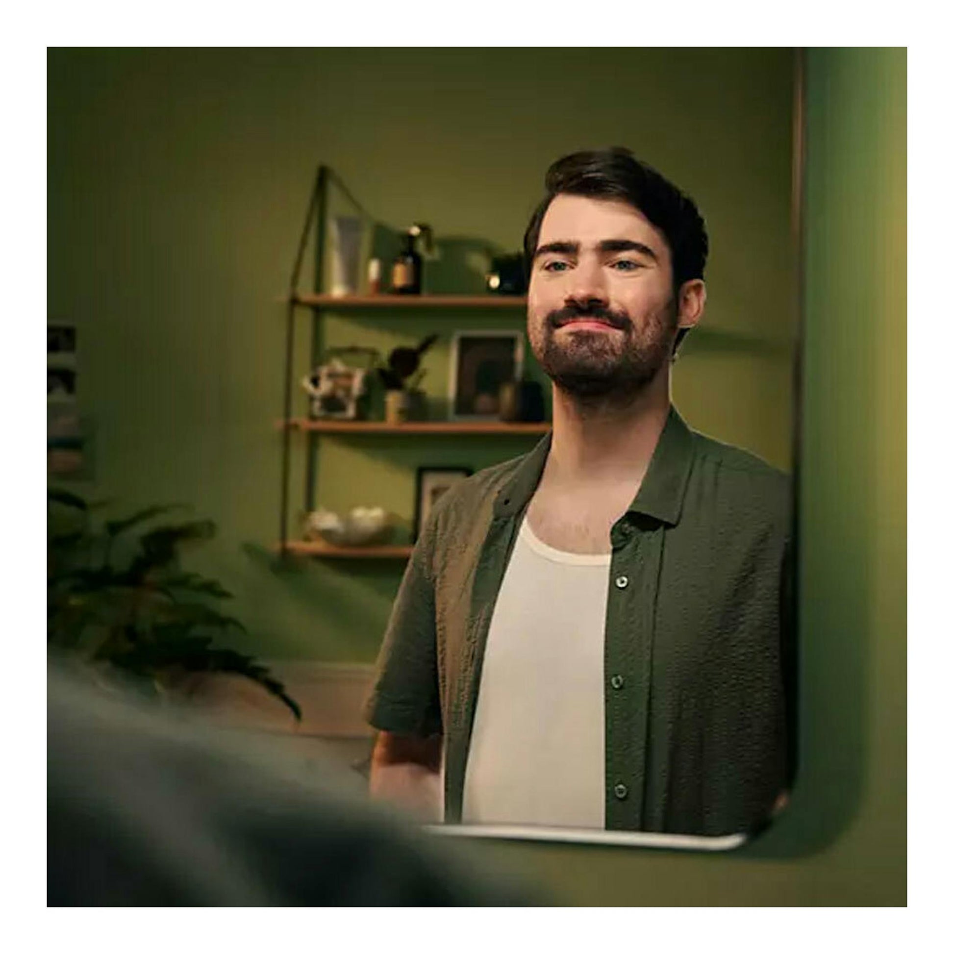 Philips MG5940/15: hombre con barba mirándose al espejo, con camisa verde y camiseta blanca.