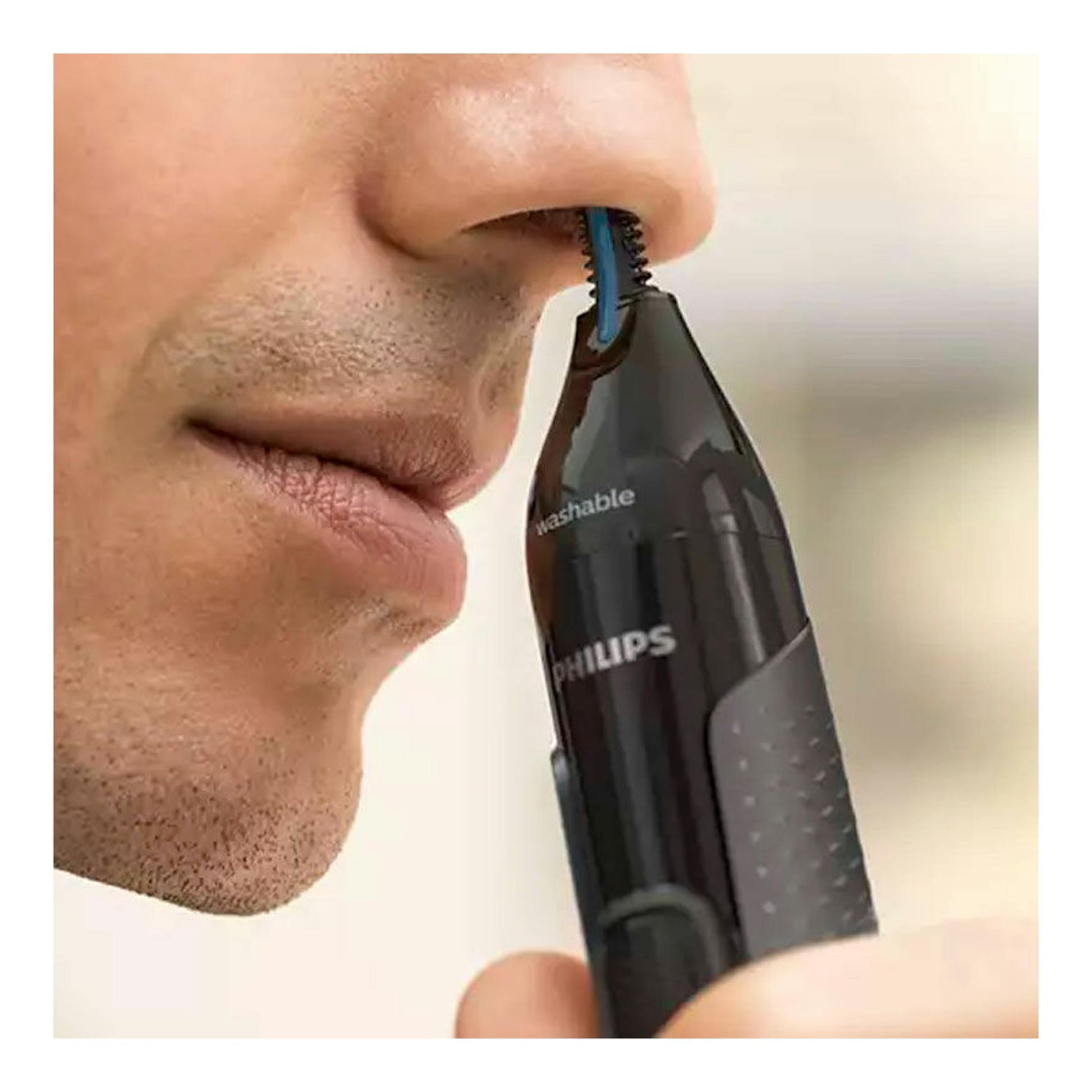 Cortapelos nasal Philips NT3650/16 negro con punta azul, en primer plano junto a la nariz de un hombre.