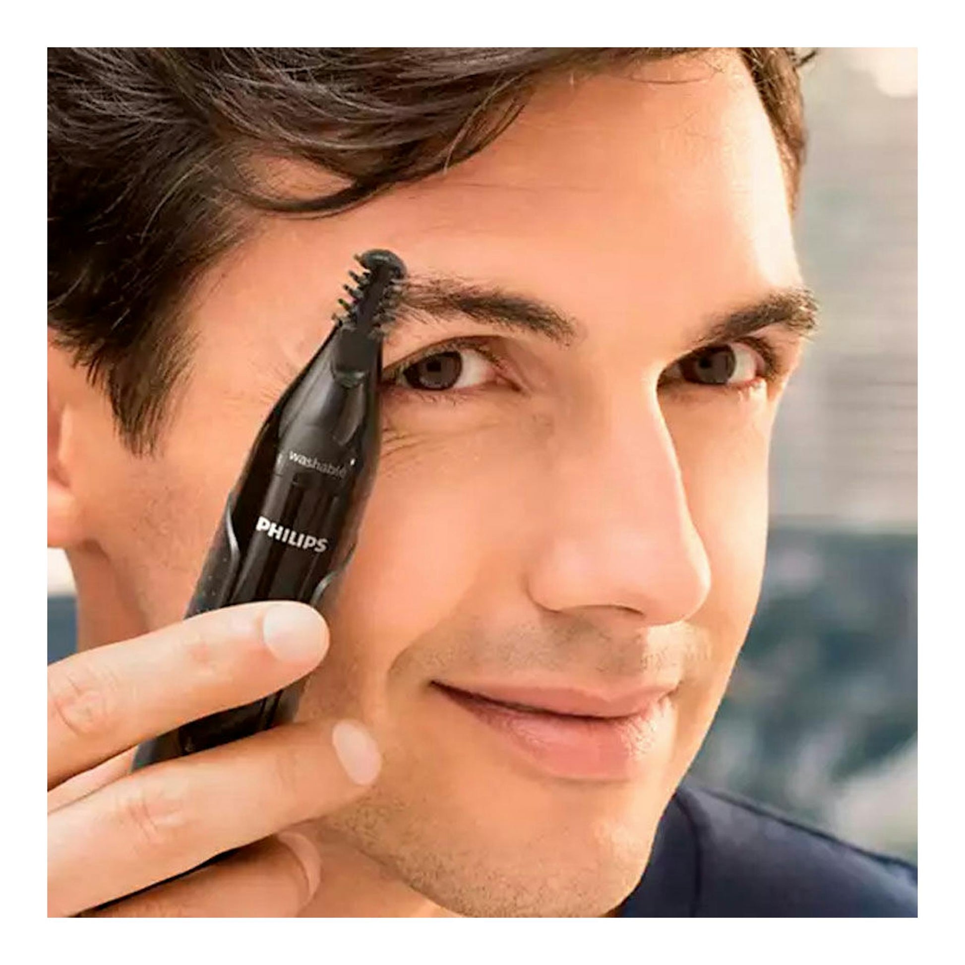 Hombre usando recortadora Philips NT3650/16 negra junto a la ceja, vista frontal en primer plano.