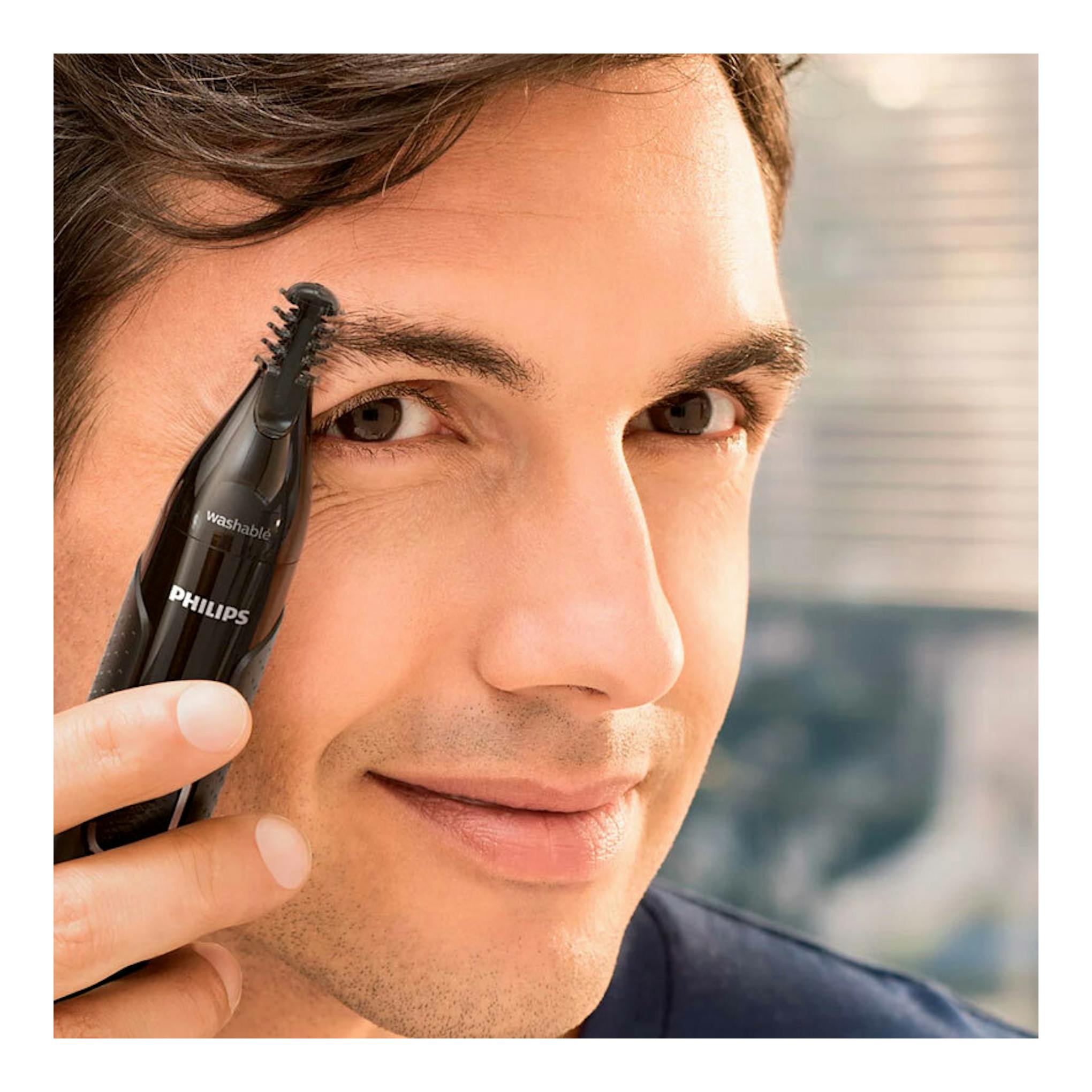 Cortapelos nasal Philips NT5650/16 negro, en uso junto a la ceja de un hombre, vista frontal.