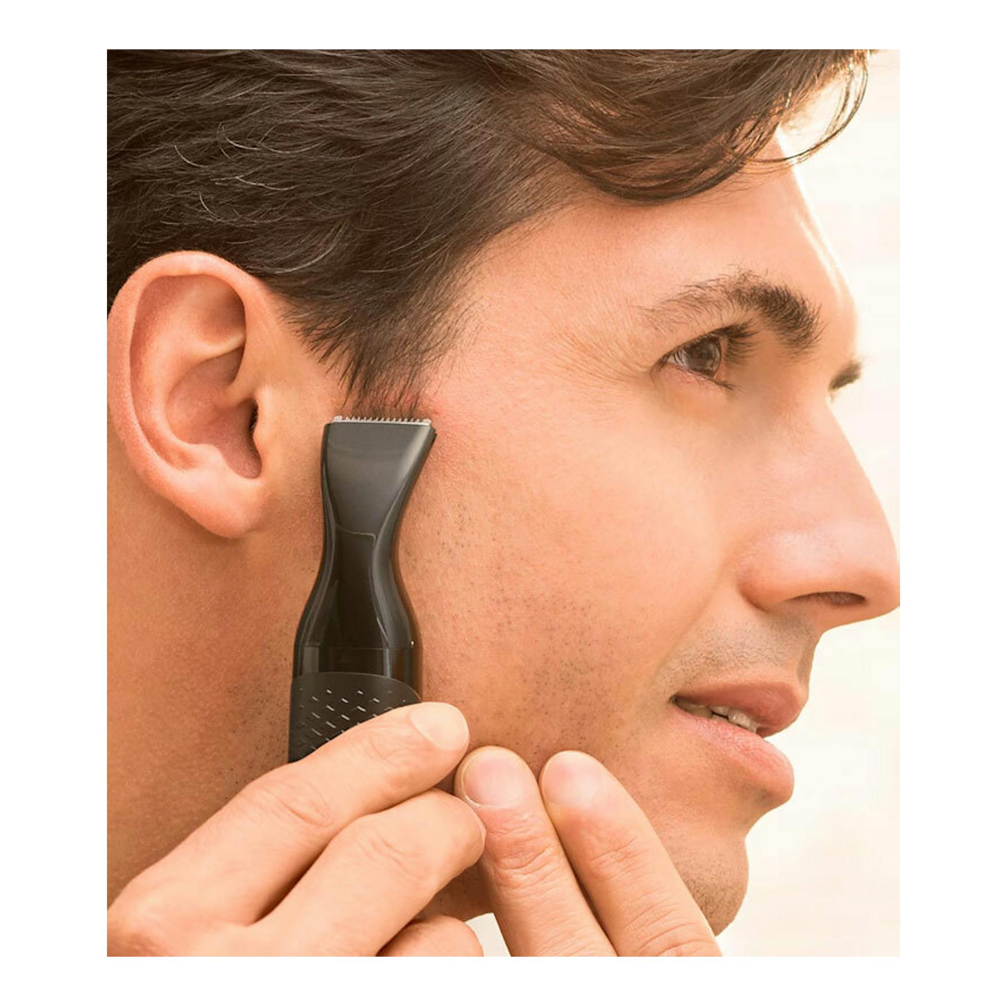 Philips NT5650/16, cortapelos negro aplicado en la mejilla junto a la oreja, vista lateral de un hombre.