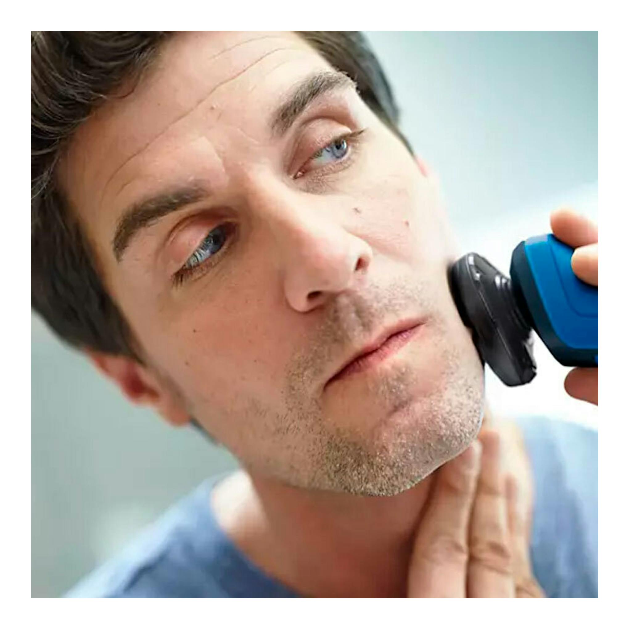 Afeitadora Philips S5466/17 azul y negra en primer plano, usada en la mejilla de un hombre.