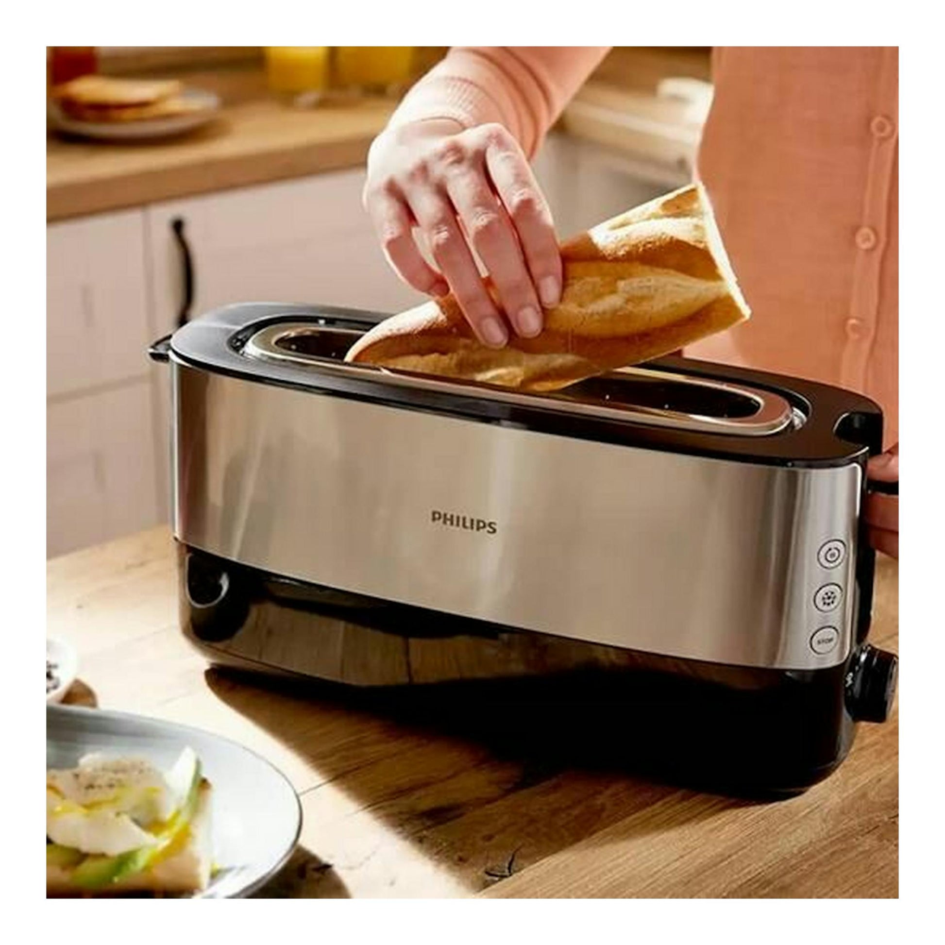 Tostador Philips HD2692/90 de acero inoxidable, vista frontal, con una mano colocando pan.