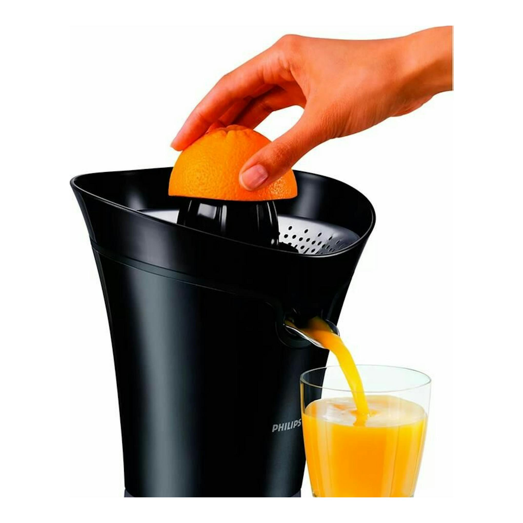 Exprimidor Philips HR2752/90 negro, vista frontal, exprimiendo una naranja y sirviendo zumo en un vaso.