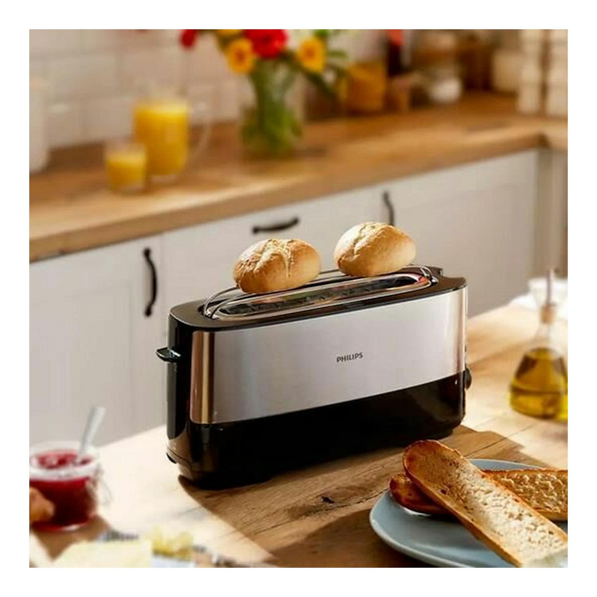 Tostador Philips HD2692/90 plateado y negro, vista frontal en una cocina, con dos panes encima.