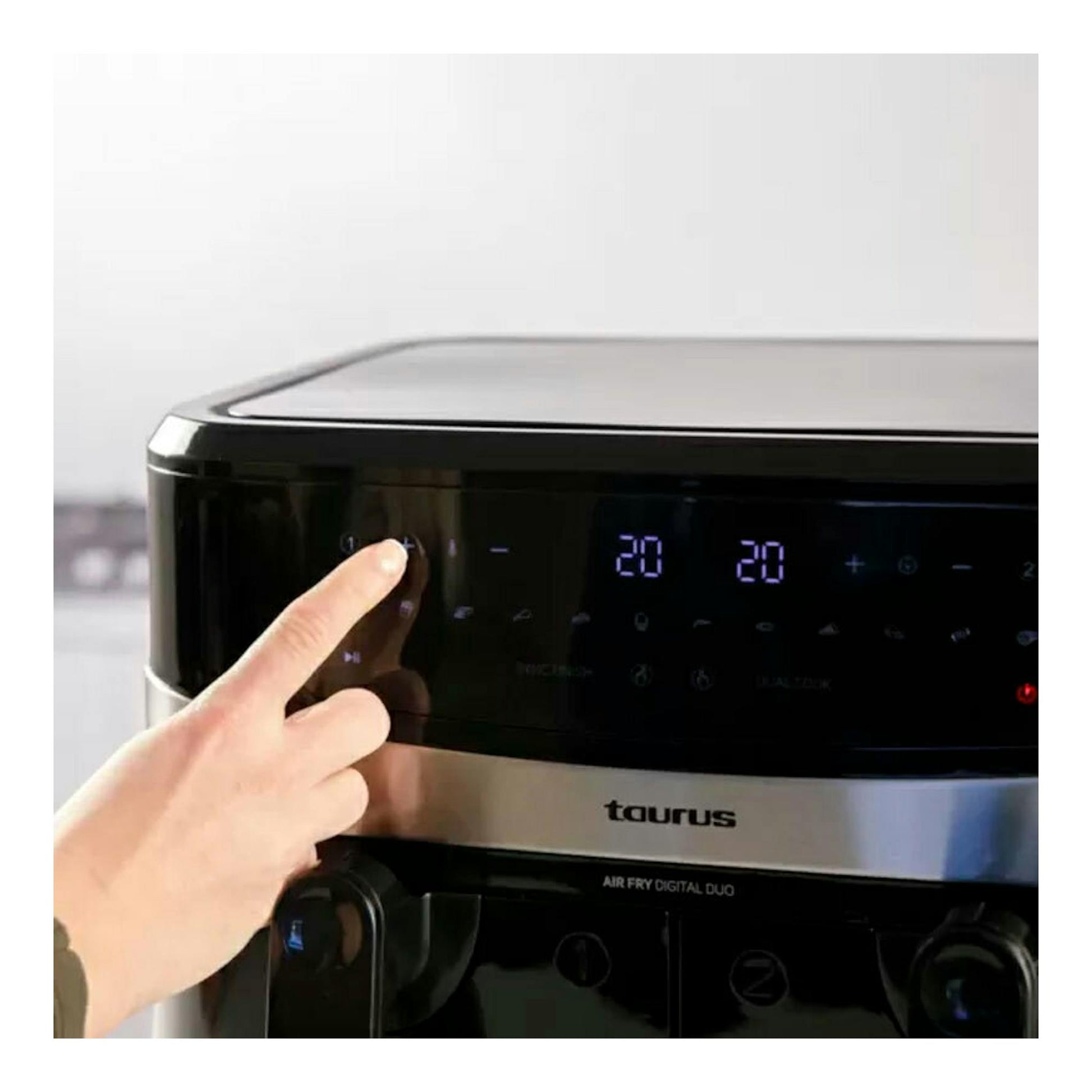 Freidora de aire Taurus Air Fry Digital Duo negra, vista frontal, con panel táctil iluminado y una mano pulsando.