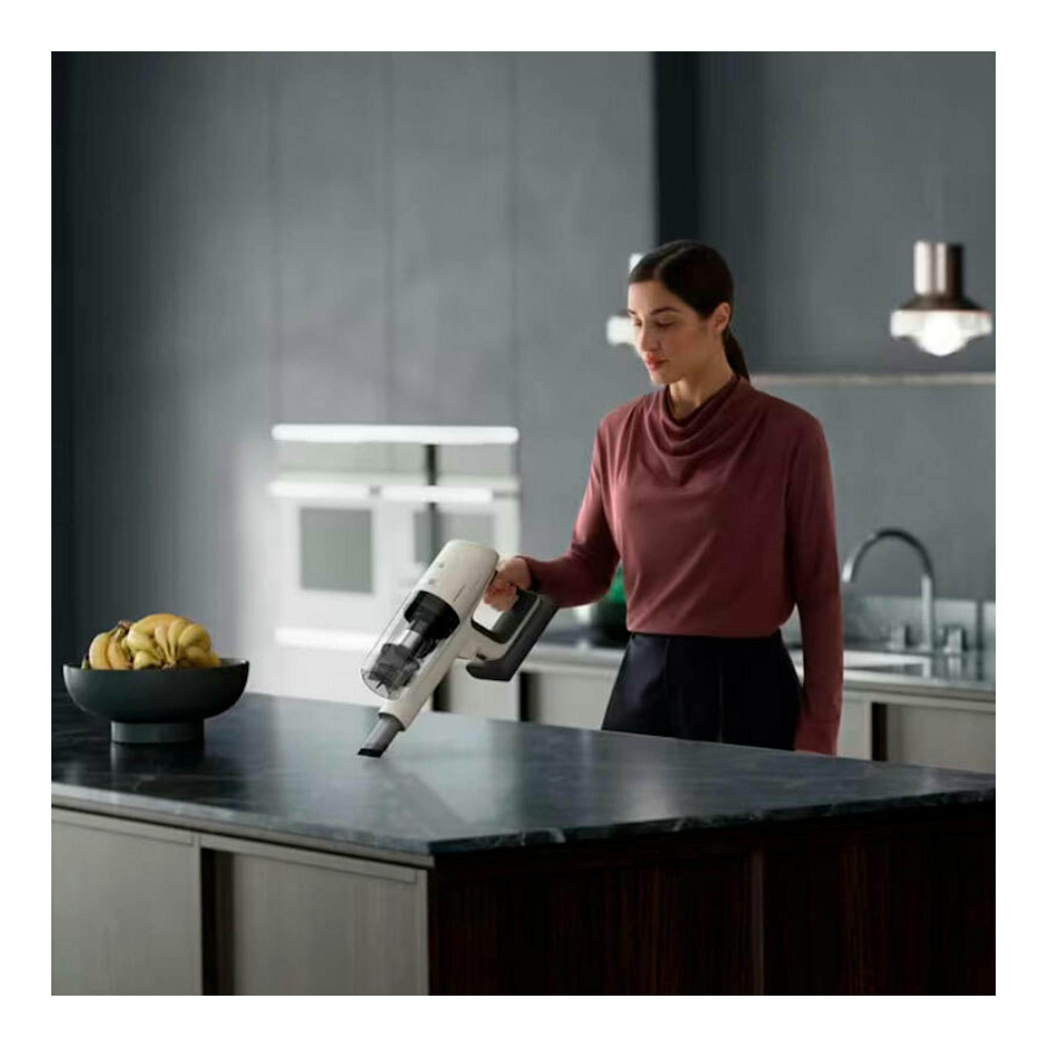 Aspirador inalámbrico AEG AP81UB25SH, blanco y negro, en uso sobre una encimera de cocina.