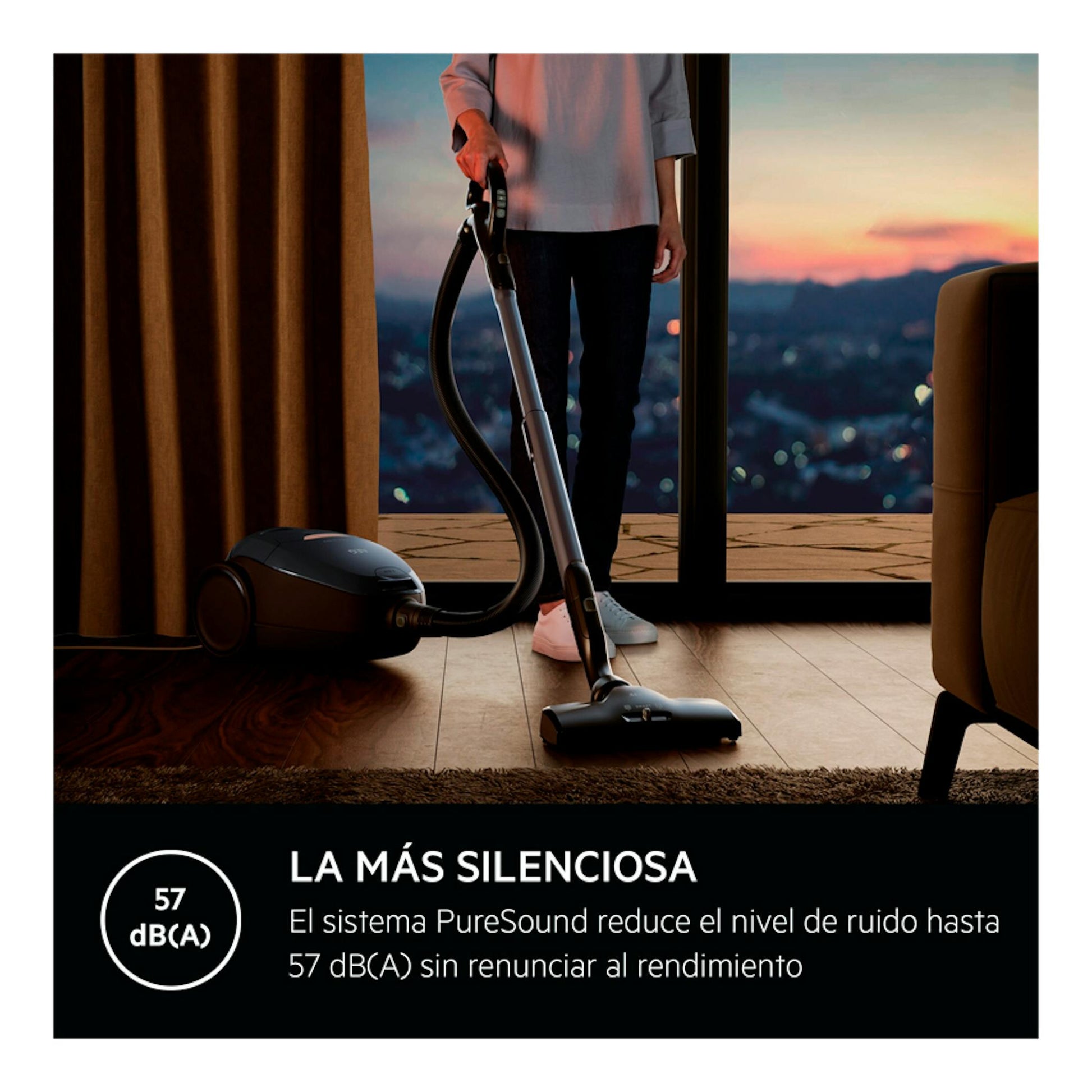 Aspirador con bolsa AEG VX82-1-5DB, vista lateral, en salón, con una persona usándolo junto a una ventana.