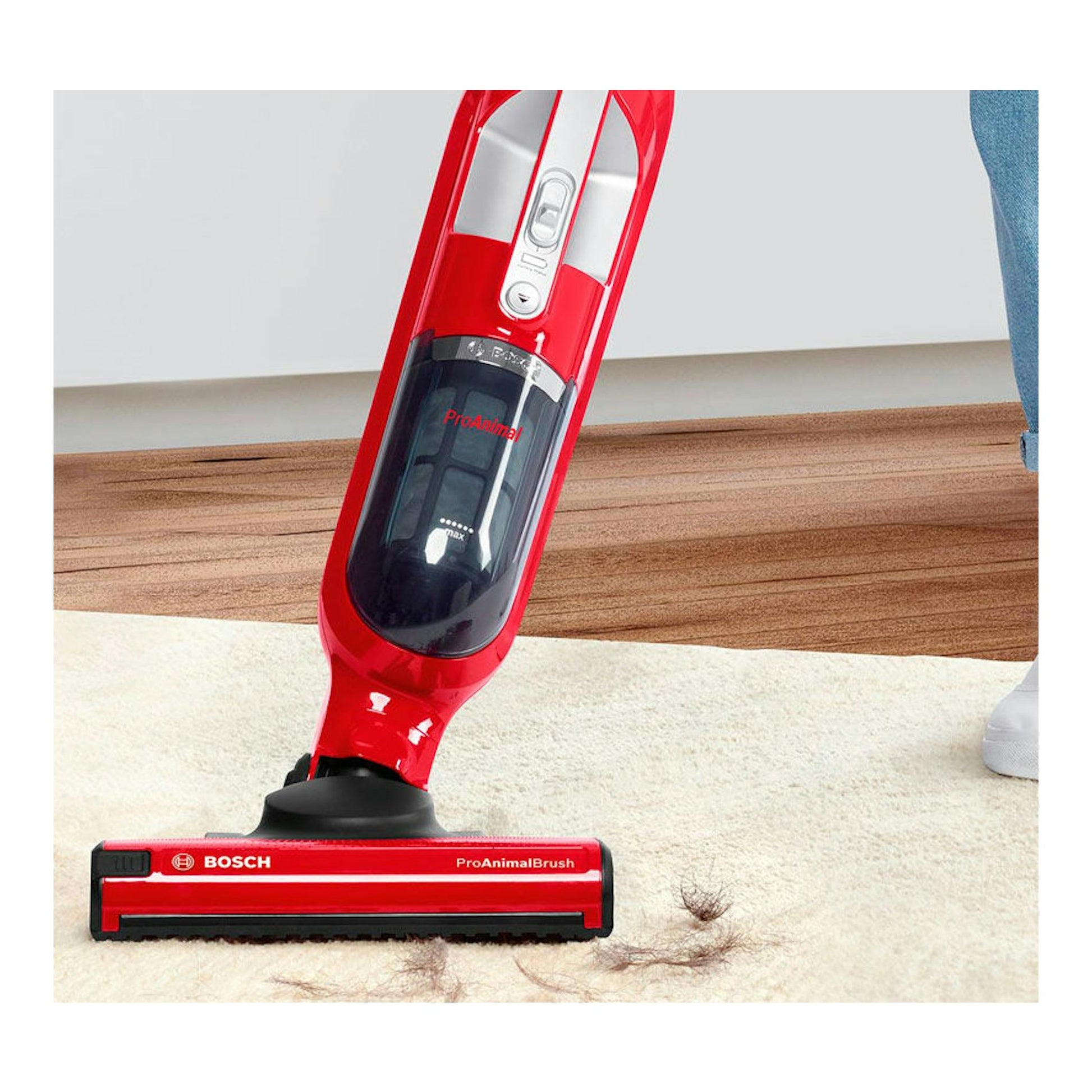 Aspirador escoba Bosch BBH3ZOO25 rojo, vista frontal inclinada, sobre alfombra con pelo visible.