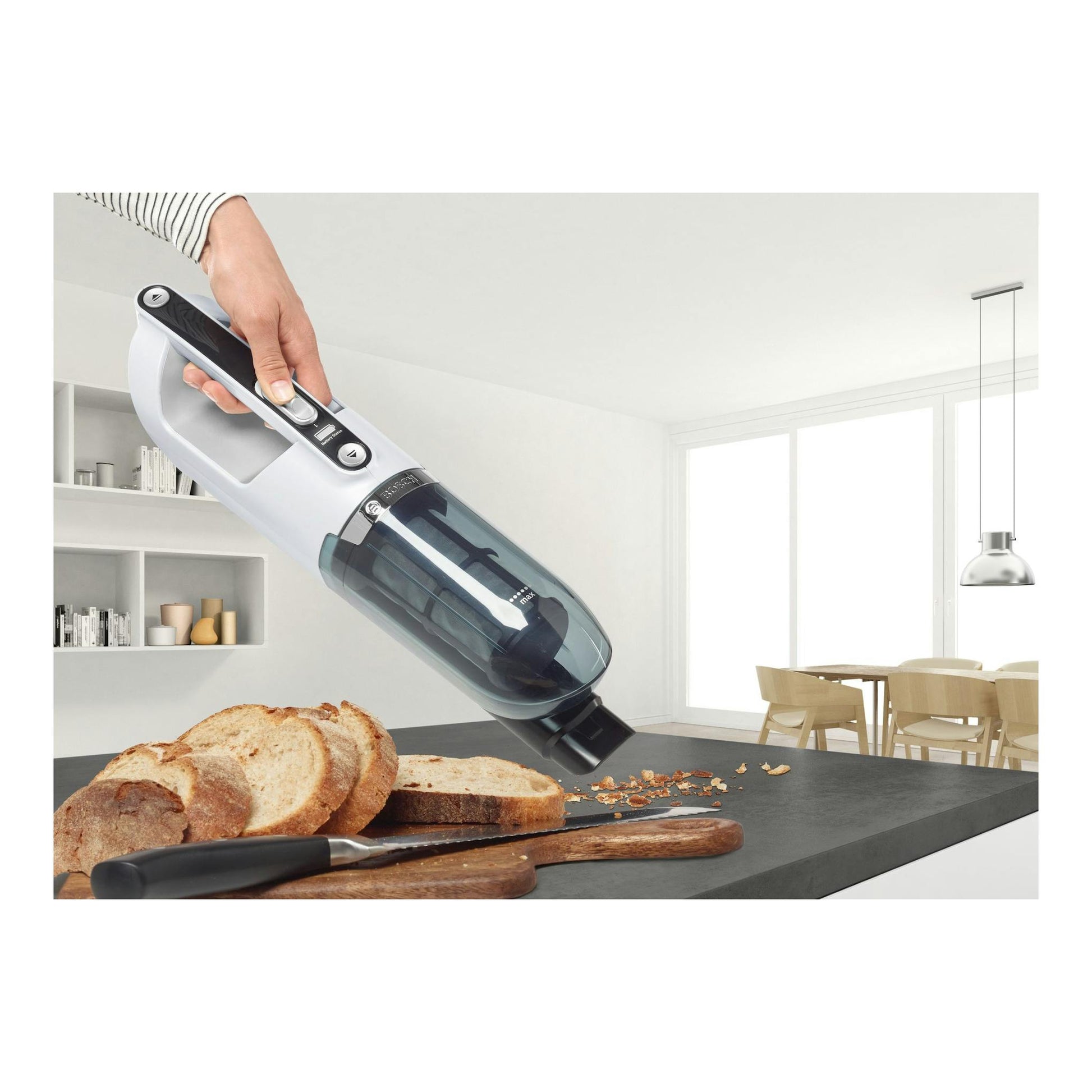 Aspirador escoba Bosch Flexxo BBH32551 blanco y negro, vista lateral, sostenido por una mano sobre migas.