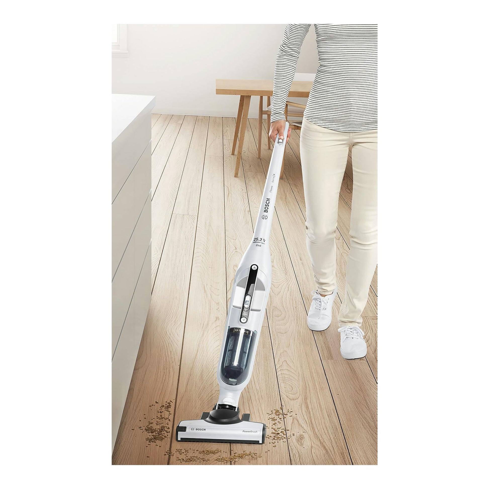 Aspirador escoba Bosch Flexxo BBH32551 blanco, en uso sobre suelo de madera por una persona.