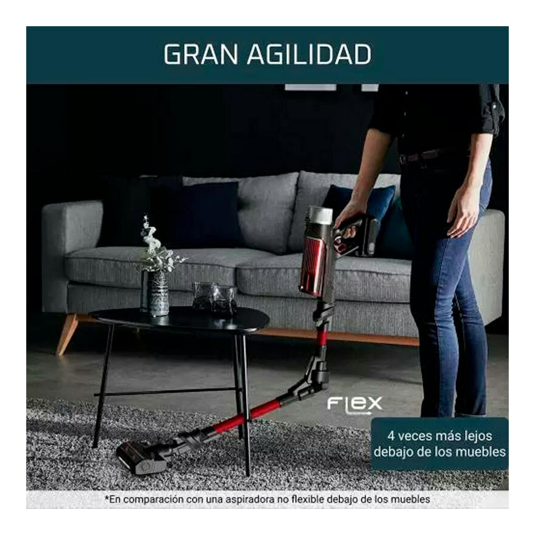 Aspirador escoba Rowenta RH2077WO rojo y negro, en uso bajo un sofá, vista lateral en salón.