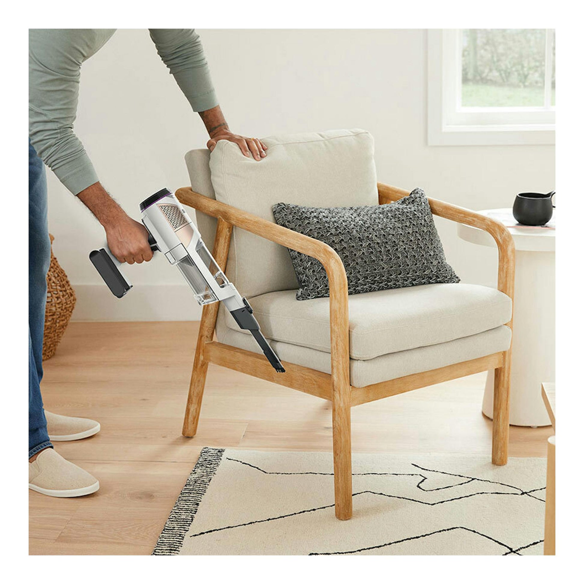 Aspirador escoba Shark IW3611EU en blanco y negro, usado junto a un sillón beige en un salón.