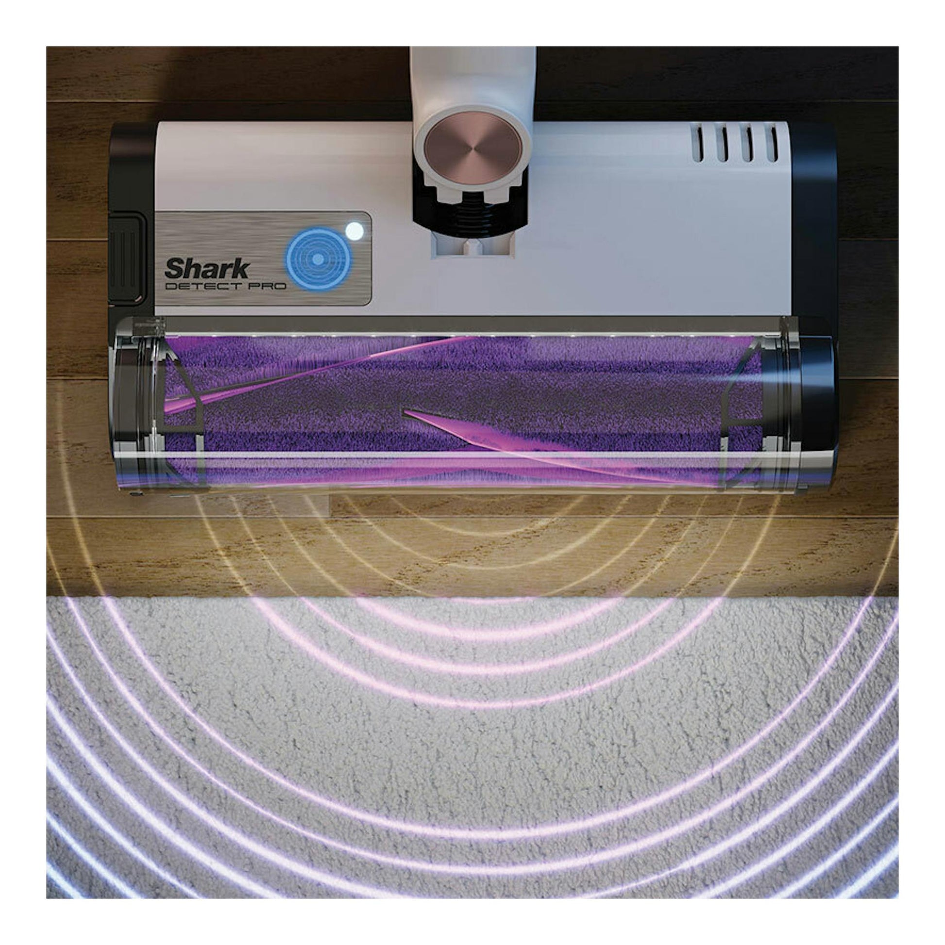 Cabezal de aspirador escoba Shark Detect Pro sobre suelo de madera junto a una alfombra, con luz morada.