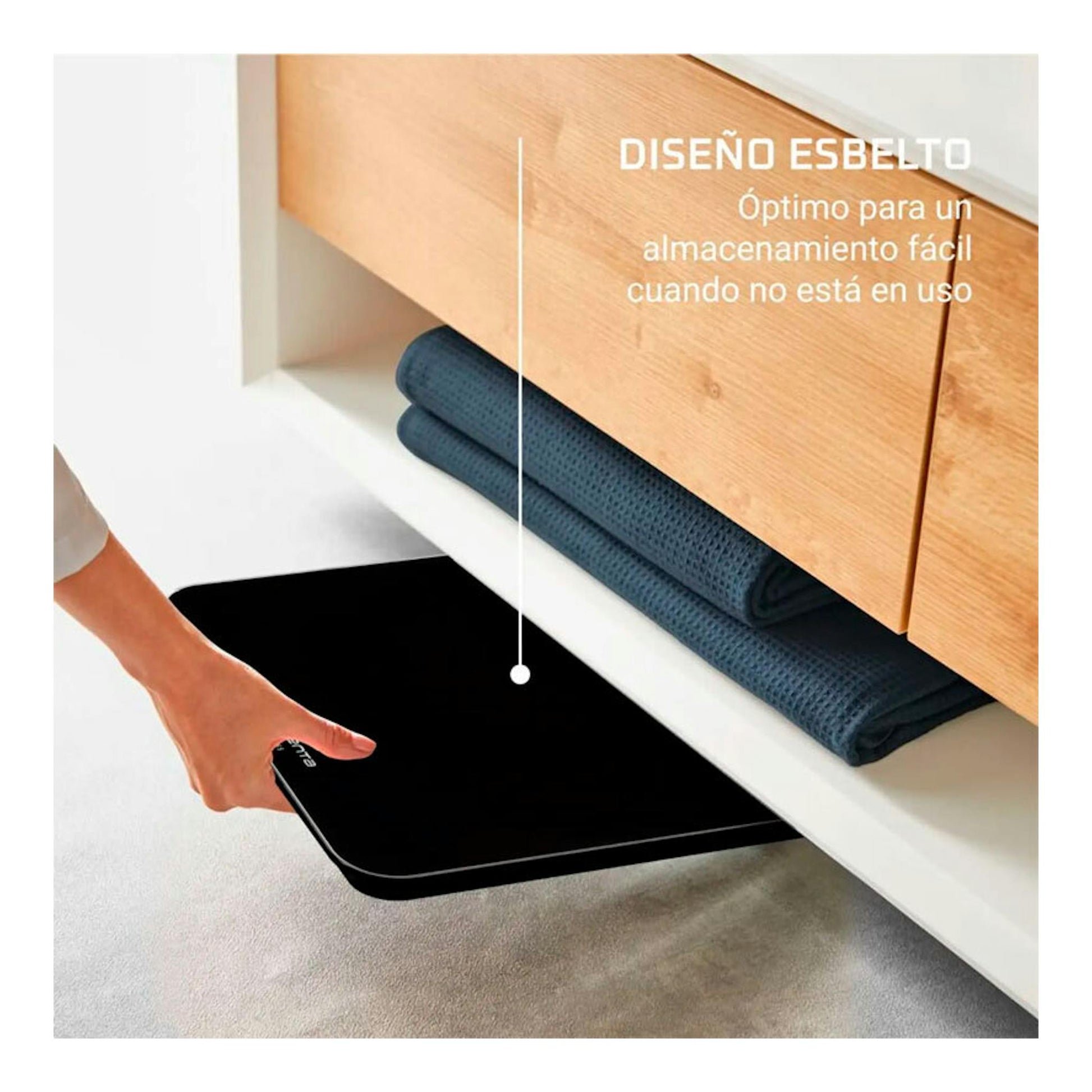 Báscula de baño Rowenta BS1800V0 negra, vista frontal, deslizándose bajo un mueble con una mano.