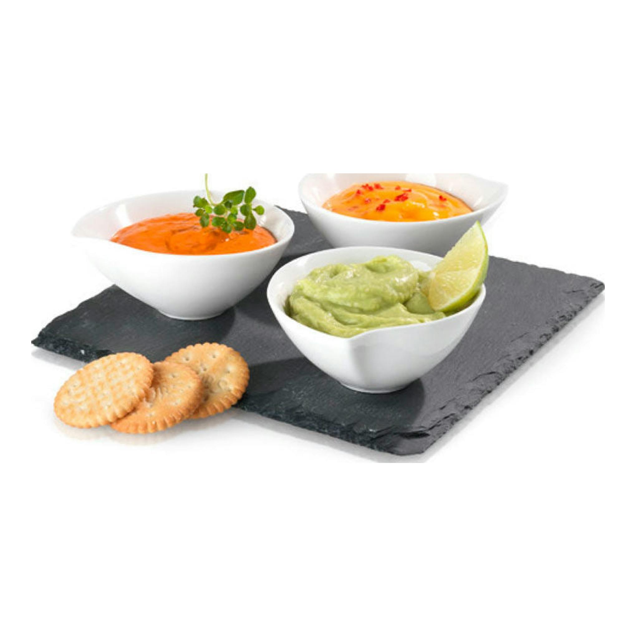 Tres cuencos con salsas roja, naranja y verde sobre pizarra negra, con galletas y una rodaja de lima.