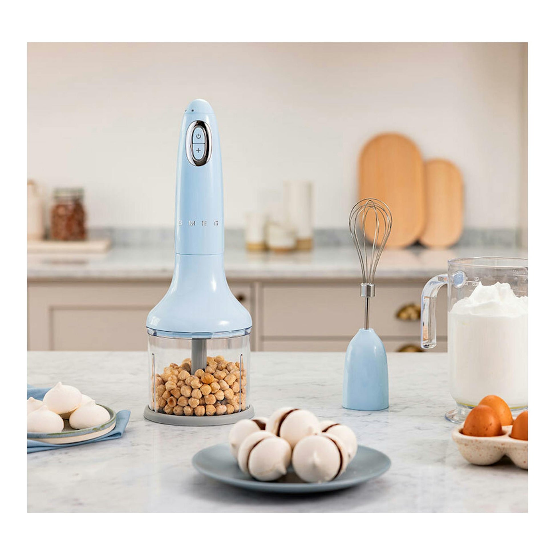 Batidora de mano Smeg HBF03PBEU azul pastel, vista frontal con vaso picador y varilla sobre encimera.