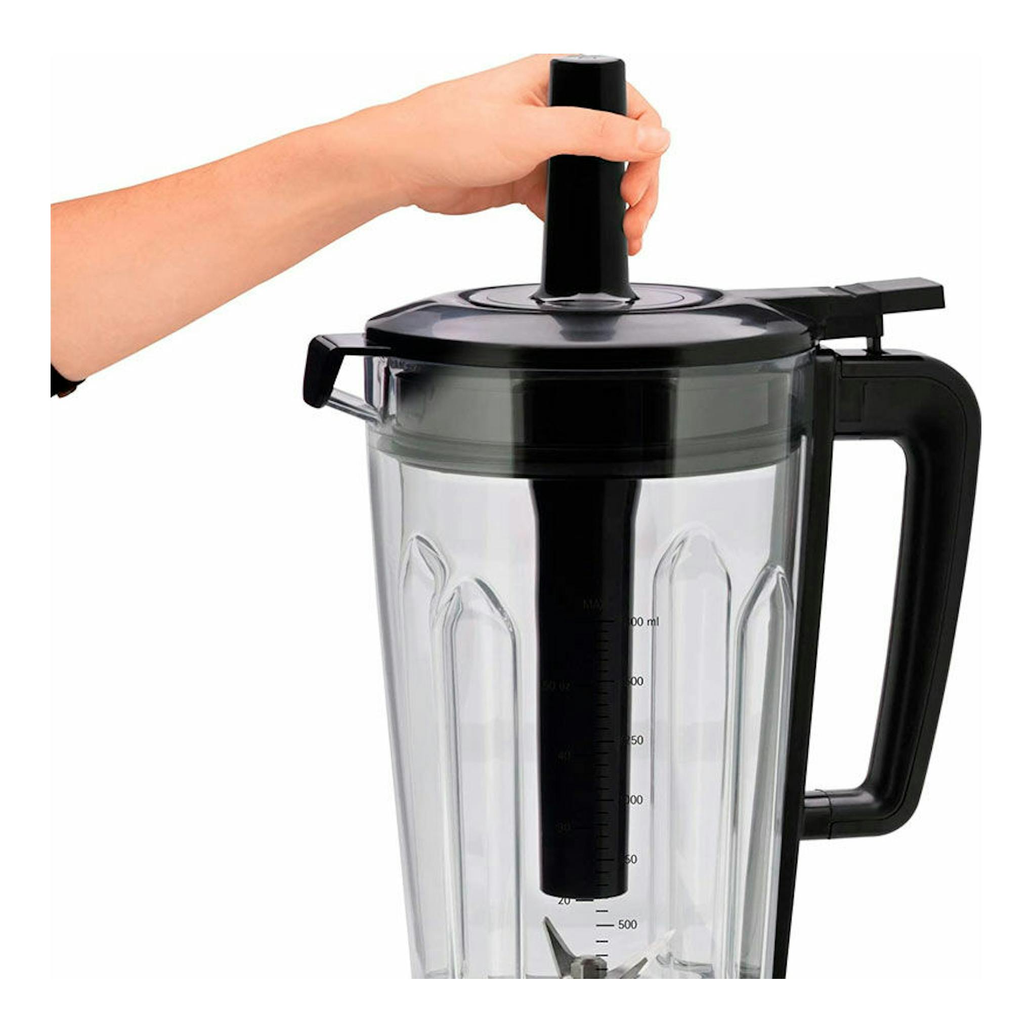Batidora de vaso WMF KULT PRO negra y transparente, vista frontal, con una mano sujetando el empujador.