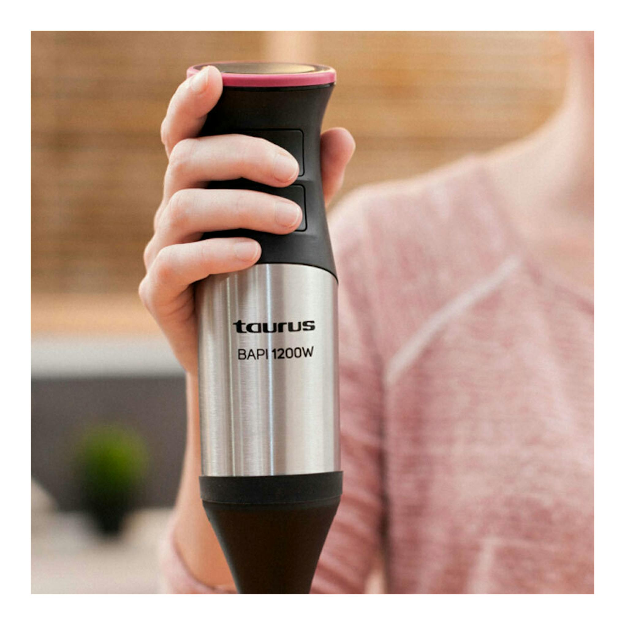 Batidora de mano Taurus Bapi 1200W, vista frontal, cuerpo de acero inoxidable y negro, sostenida con una mano.