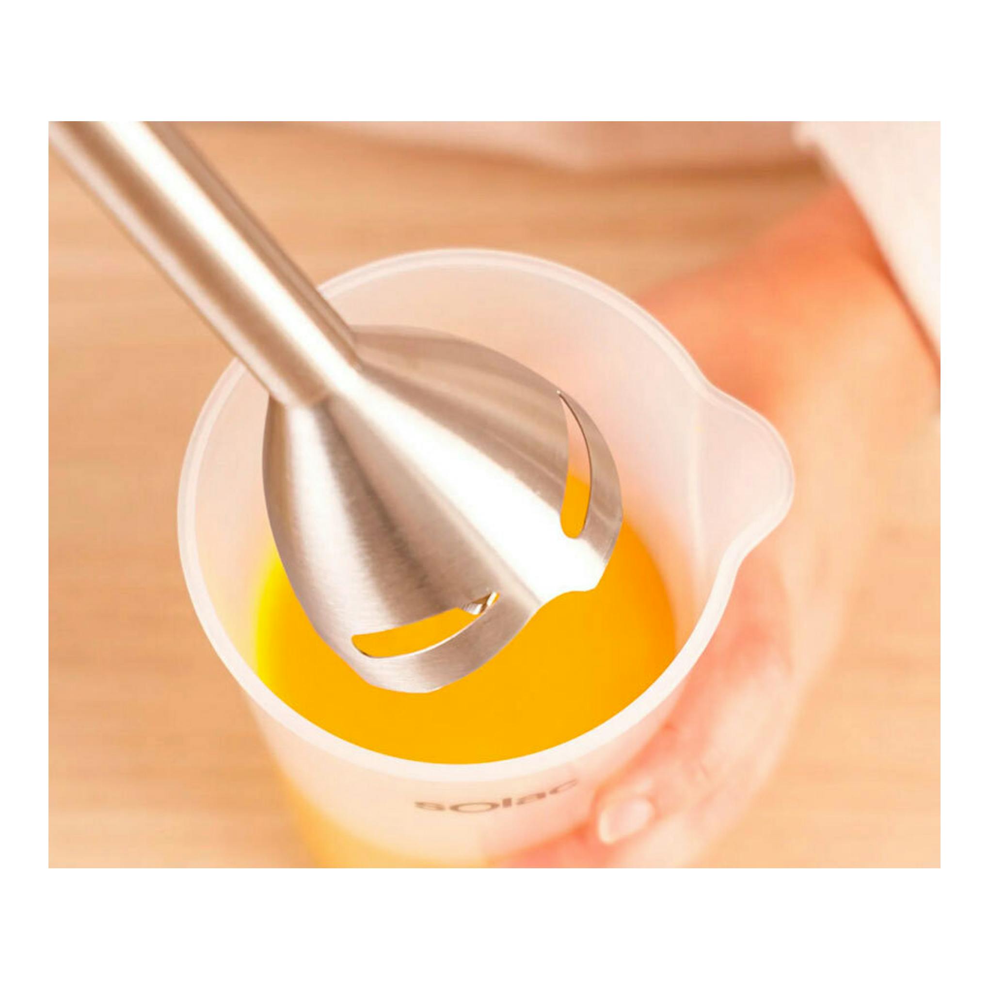 Batidora de mano Solac BA5618, vista cenital, mezclando líquido naranja en un vaso medidor blanco.