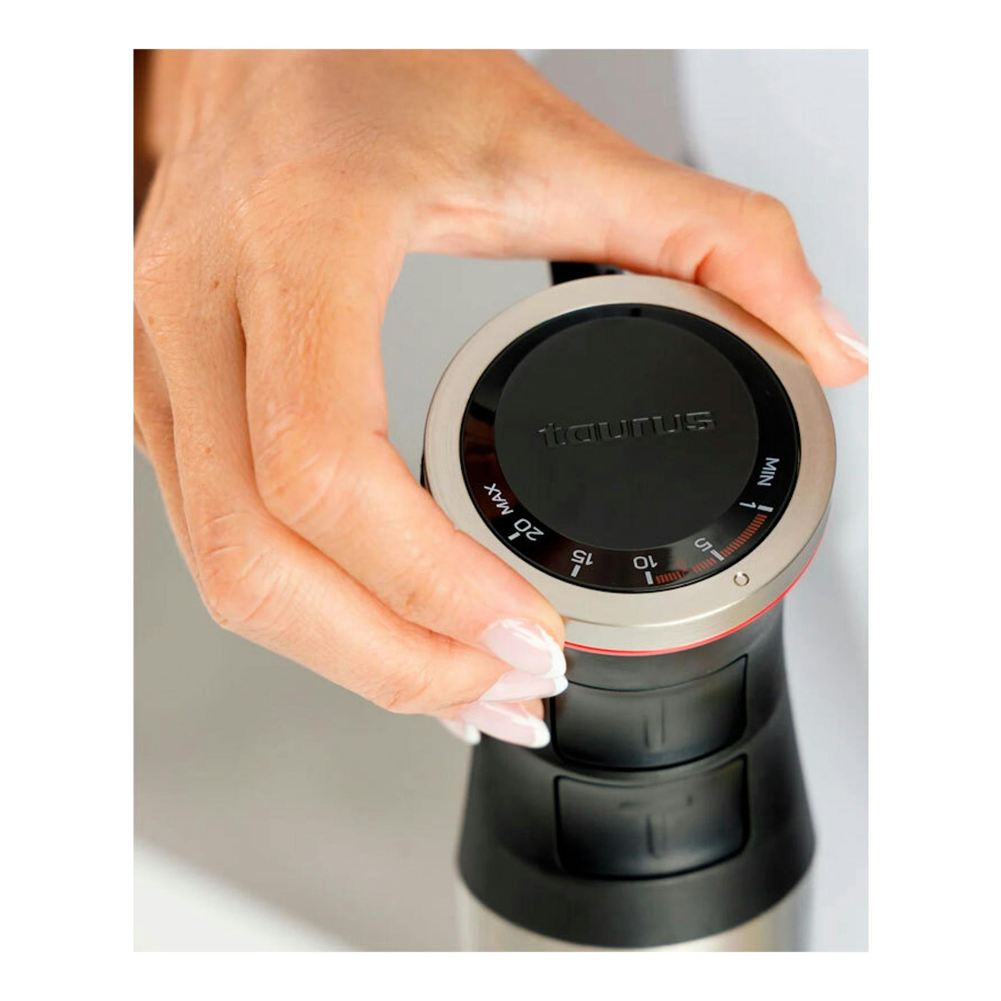 Batidora de mano Taurus Bapi 1500 Inox, vista cenital del mando negro y anillo metálico, con una mano sujetándola.