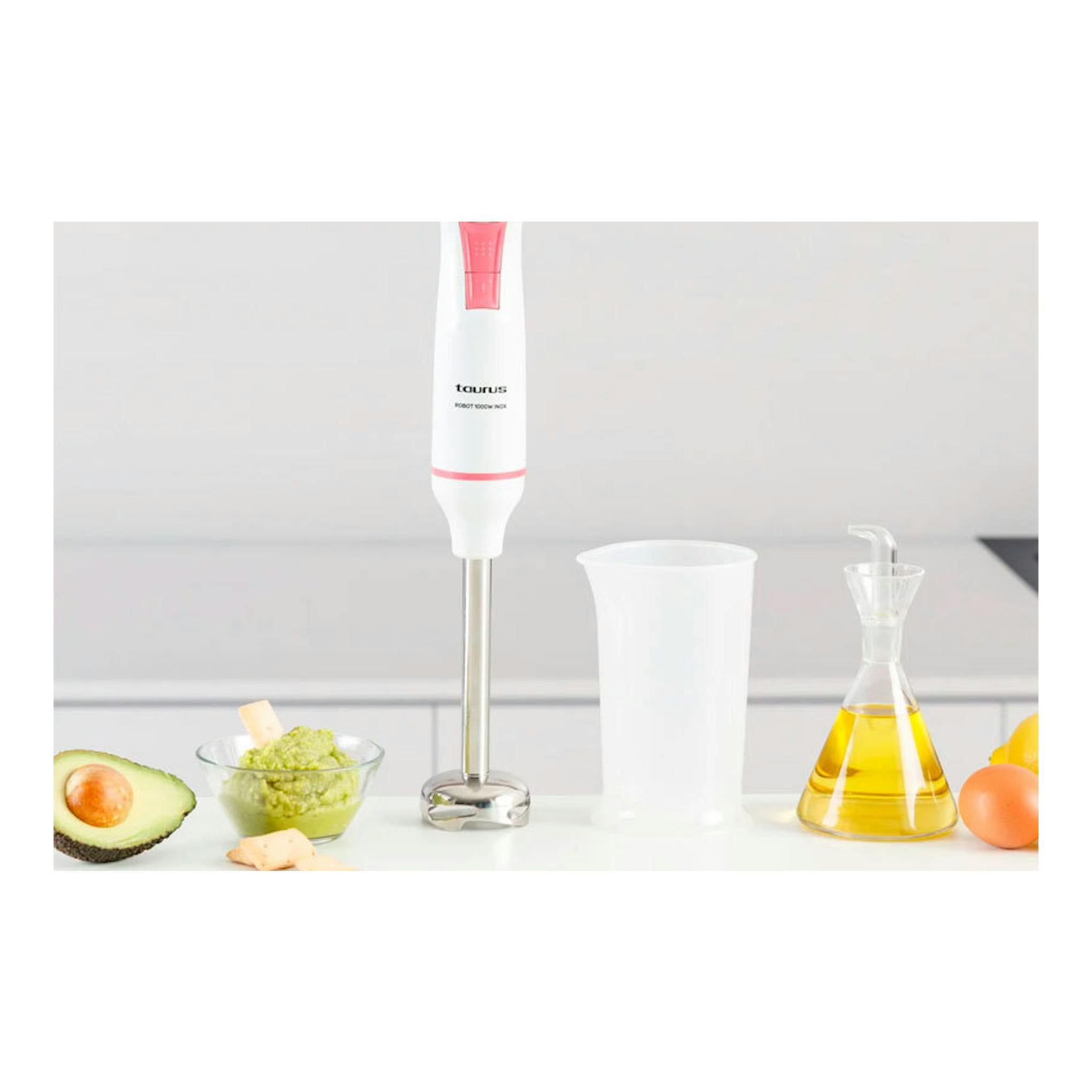 Batidora de mano Taurus Robot 1000 Inox blanca con detalles rosas, vista frontal, junto a vaso medidor.