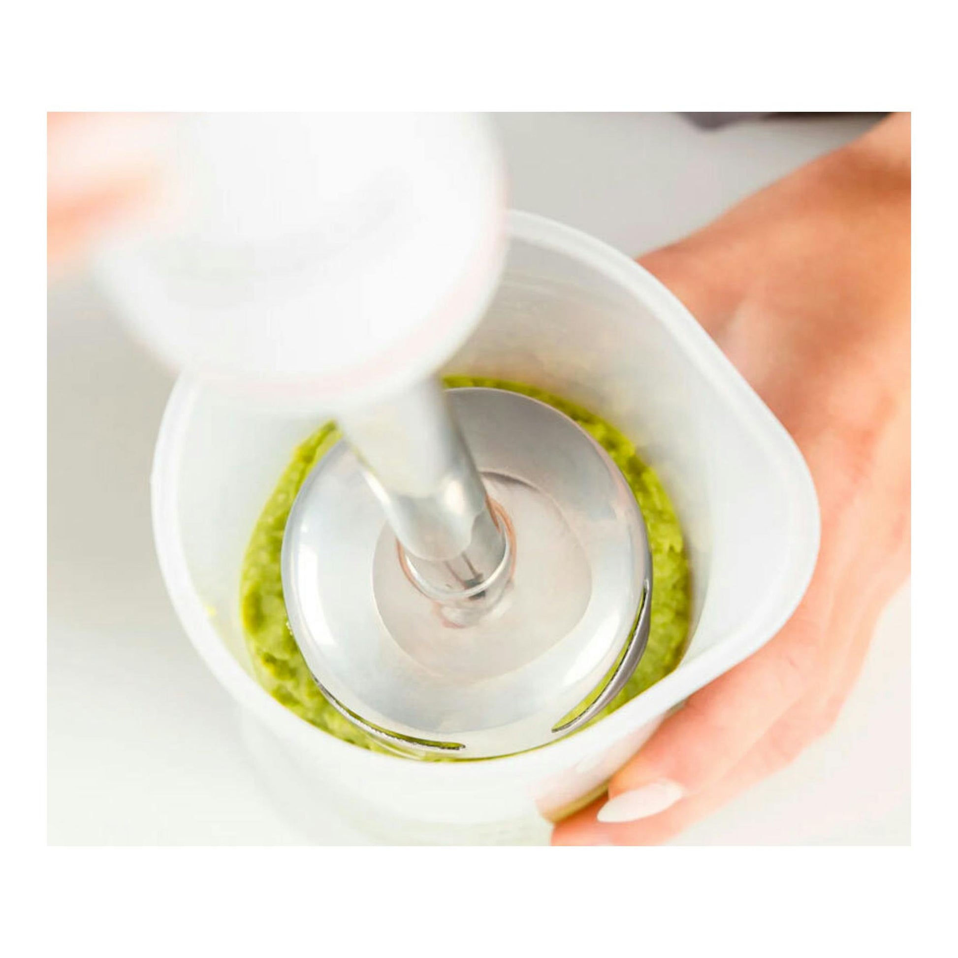 Batidora de mano Taurus Robot 1000 Inox, vista superior, triturando salsa verde en un vaso blanco.
