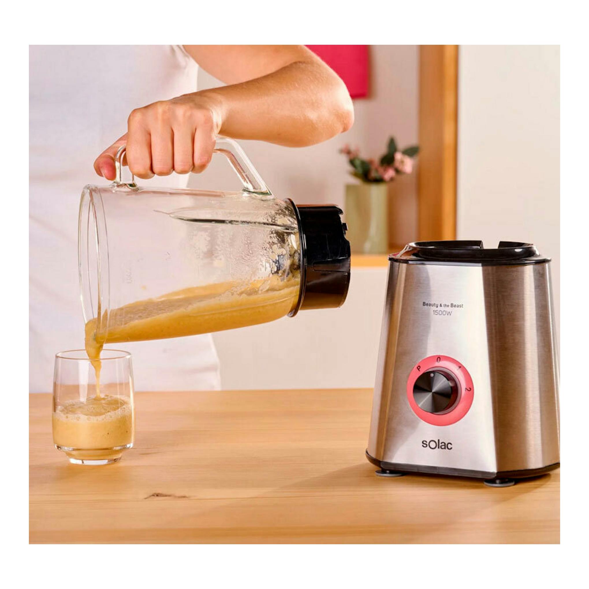 Batidora vaso Solac BV5728 de acero inoxidable, con jarra de vidrio vertiendo zumo en un vaso.