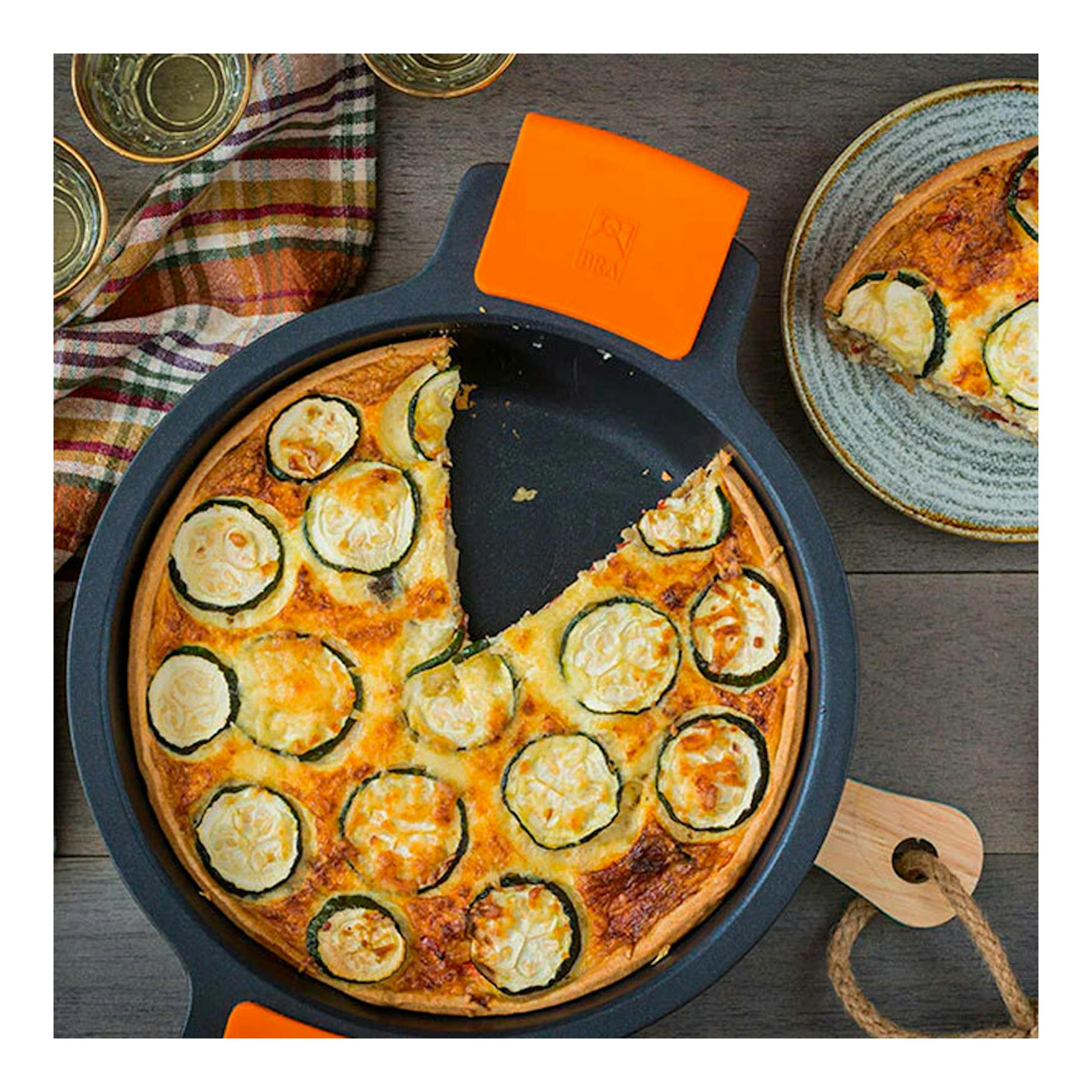 Cacerola baja Bra Efficient 28 negra, vista cenital, con quiche de calabacín y mango naranja.