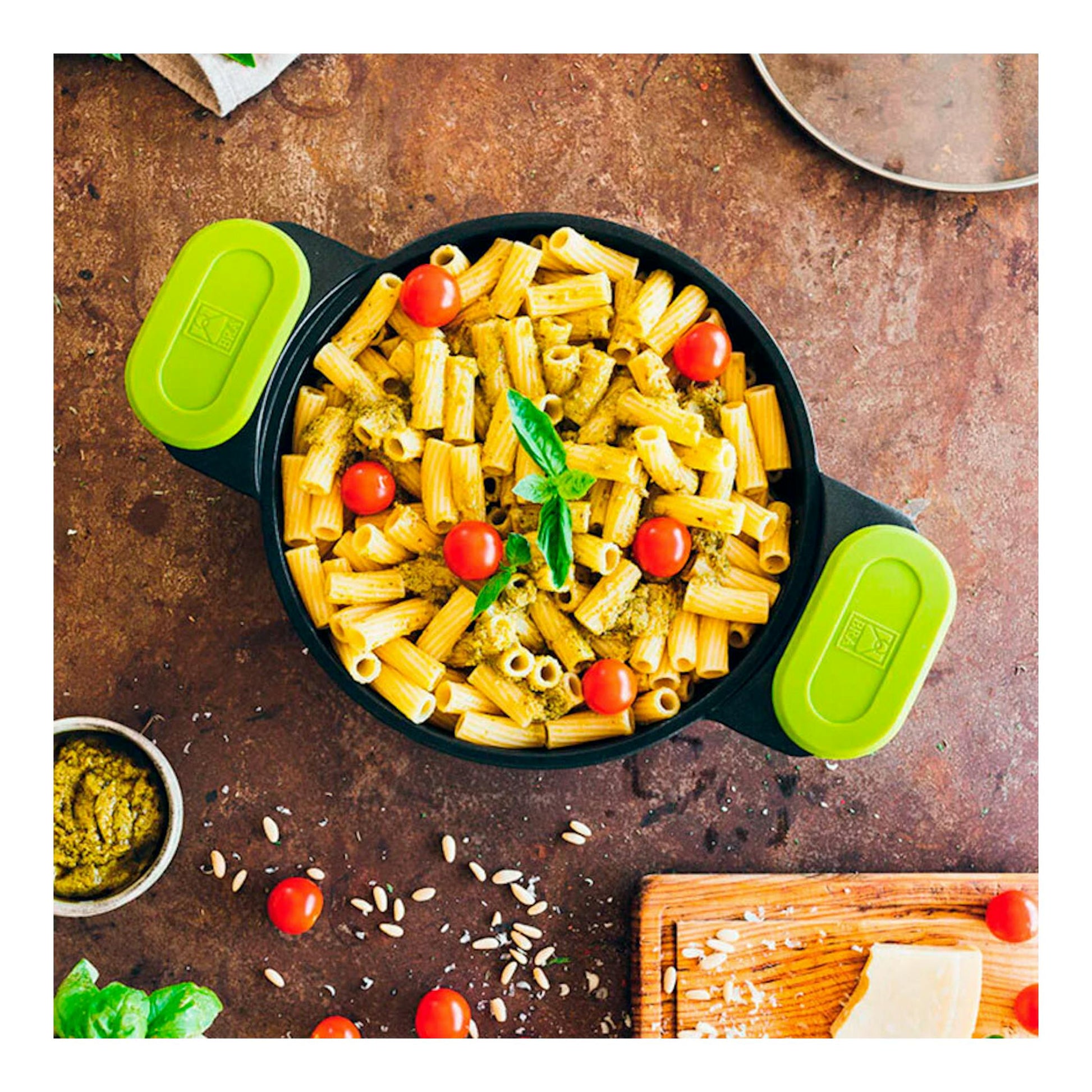 Vista cenital de cacerola Bra Foodie negra de 20 cm con asas verde lima, llena de pasta y tomates cherry.