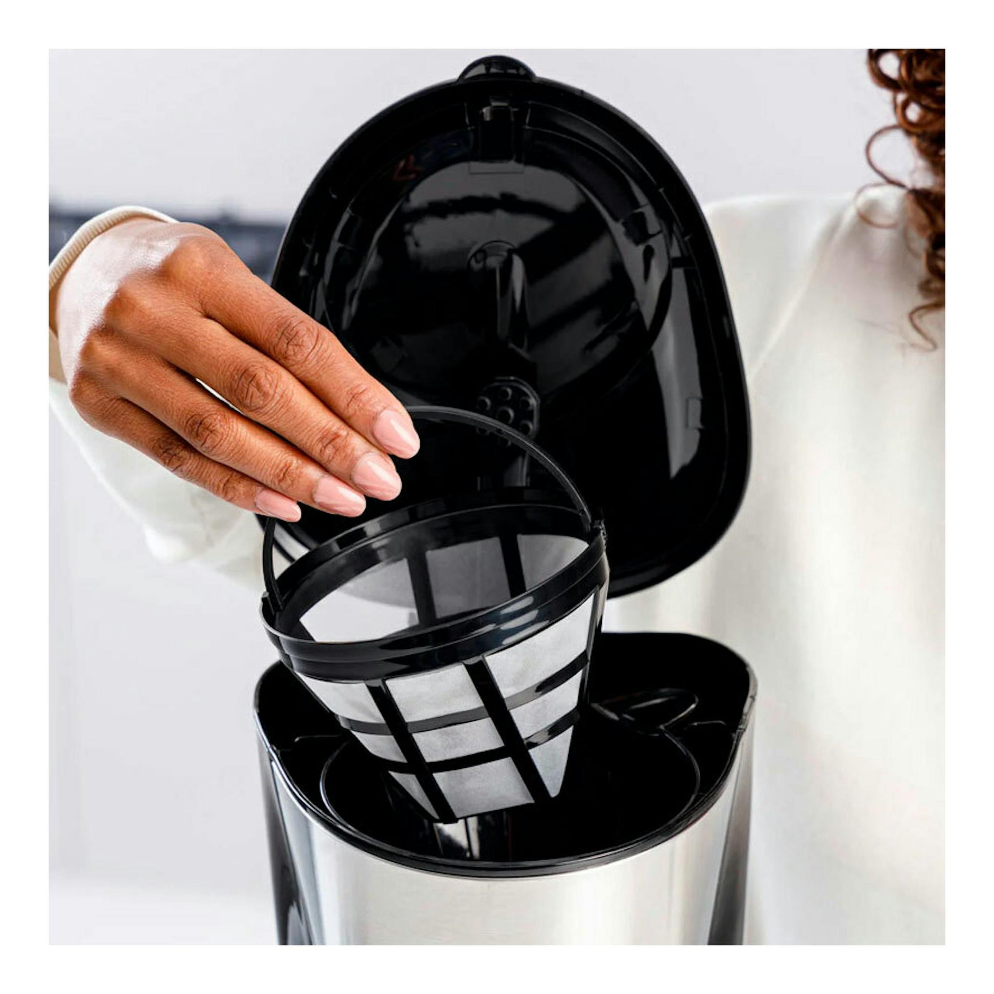 Cafetera de goteo Taurus Verona 12 Inox, vista frontal abierta en negro e inox, con mano colocando el filtro.