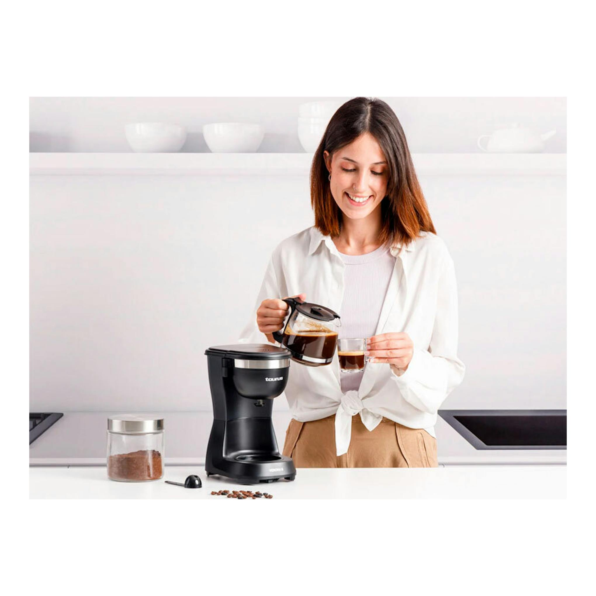 Cafetera de goteo Taurus Verona 6 negra, vista frontal, con una mujer sirviendo café en una taza.