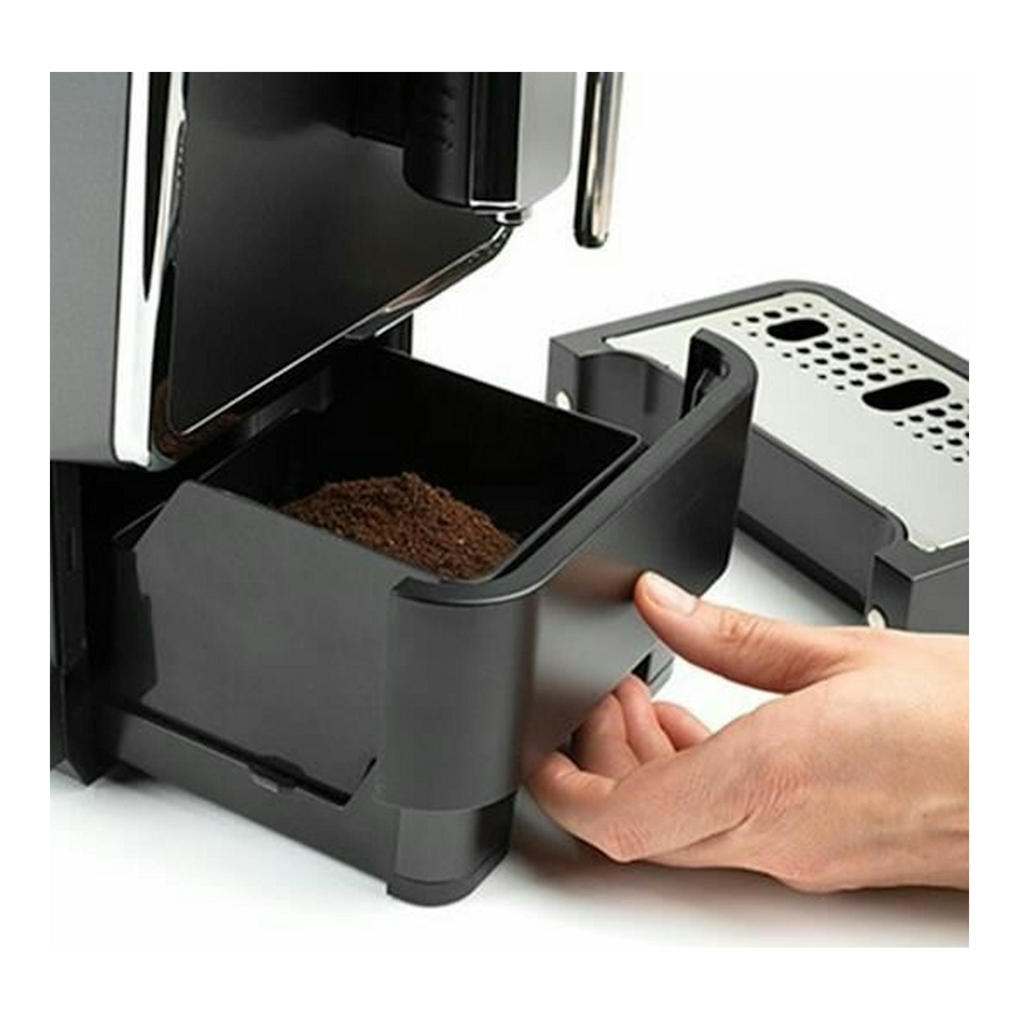 Cafetera espresso Solac CA4810 negra y plateada, vista frontal parcial, con cajón de posos extraído por una mano.