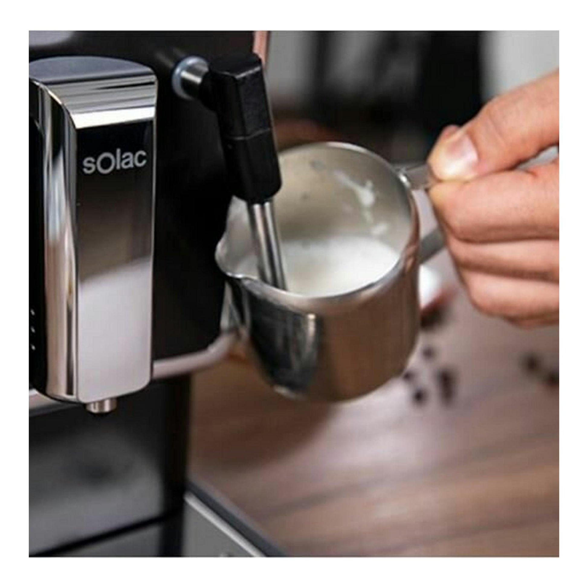 Cafetera espresso Solac negra y plateada, vista frontal, con vaporizador en una jarra metálica con leche.